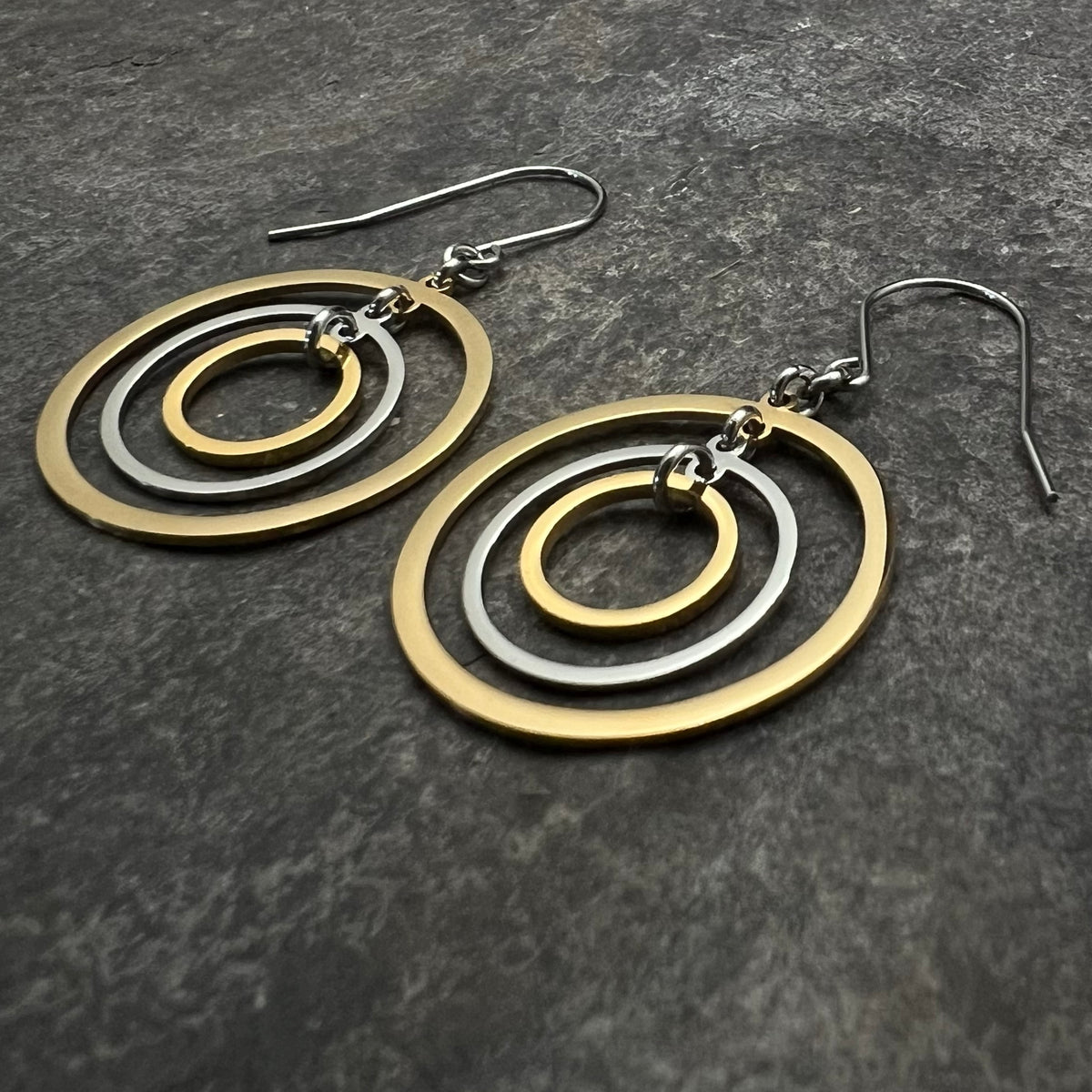 Mixed-metal stainless steel earrings with three interlinked concentric gold and silver rings and stainless steel ear hooks, 5 cm length — Lawless Jewellery.
