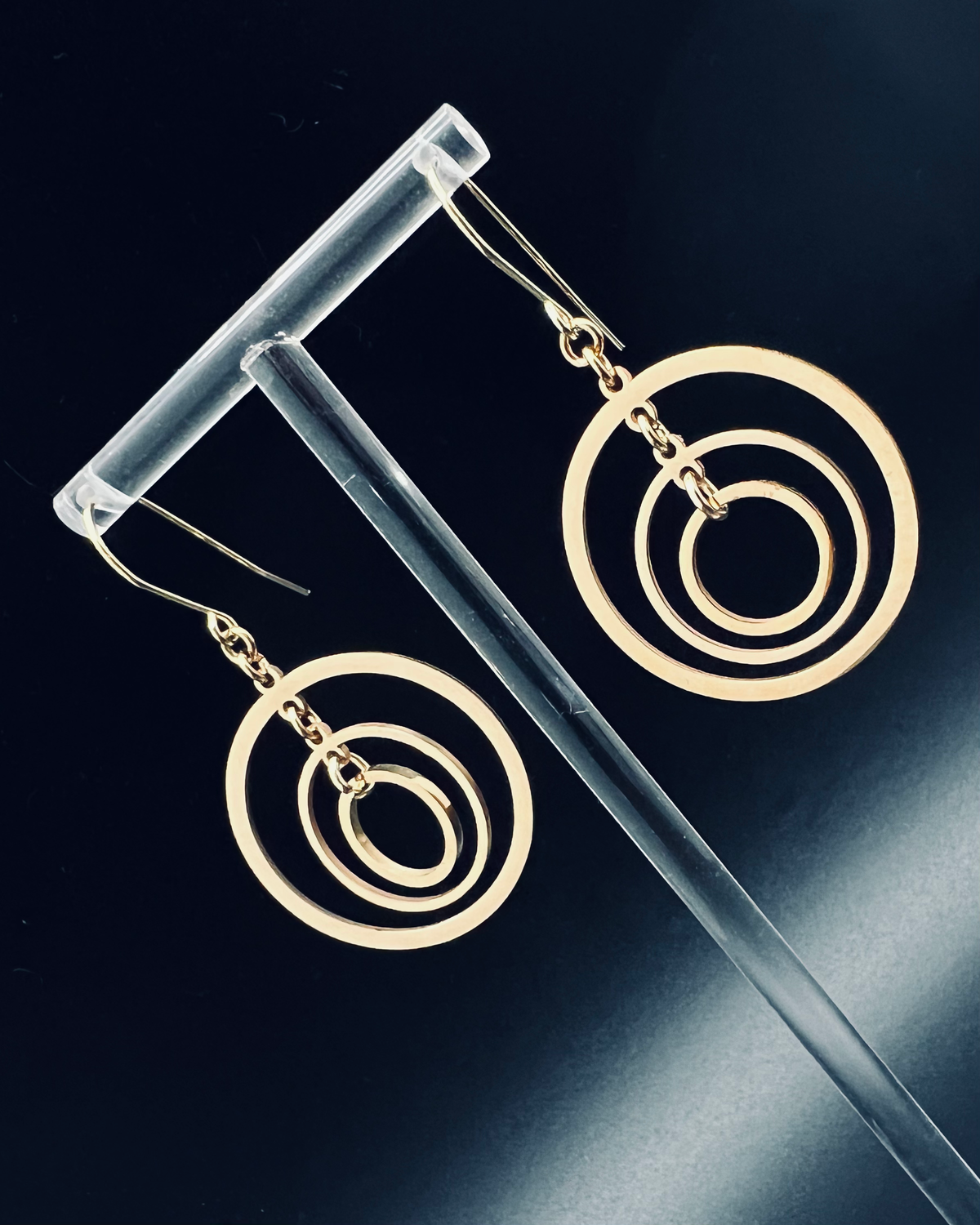 Gold triple-ring halo earrings with three interlinked high-polish rings and gold-plated stainless steel ear hooks, 5 cm length — Lawless Jewellery.