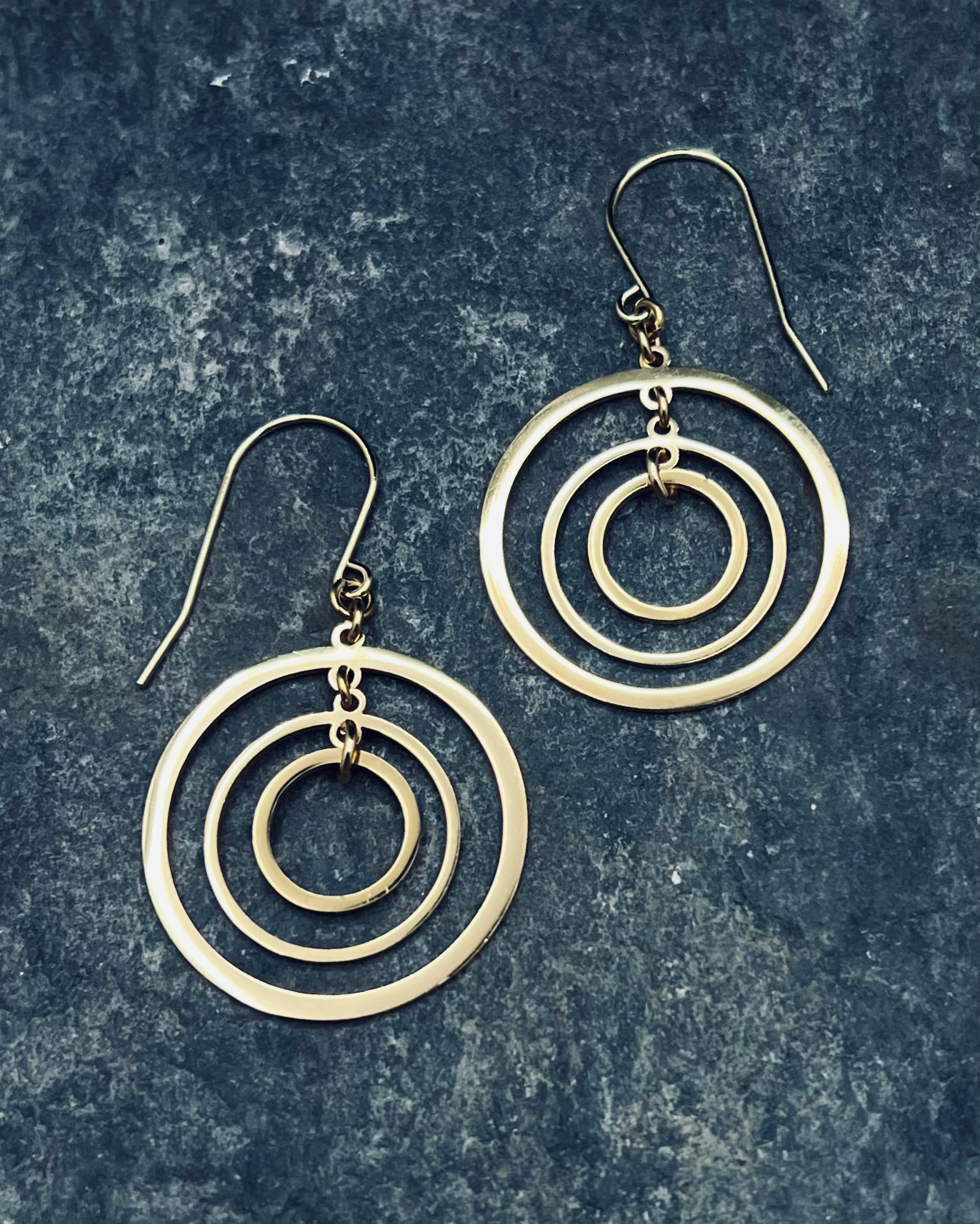 Gold triple-ring halo earrings with three interlinked high-polish rings and gold-plated stainless steel ear hooks, 5 cm length — Lawless Jewellery.