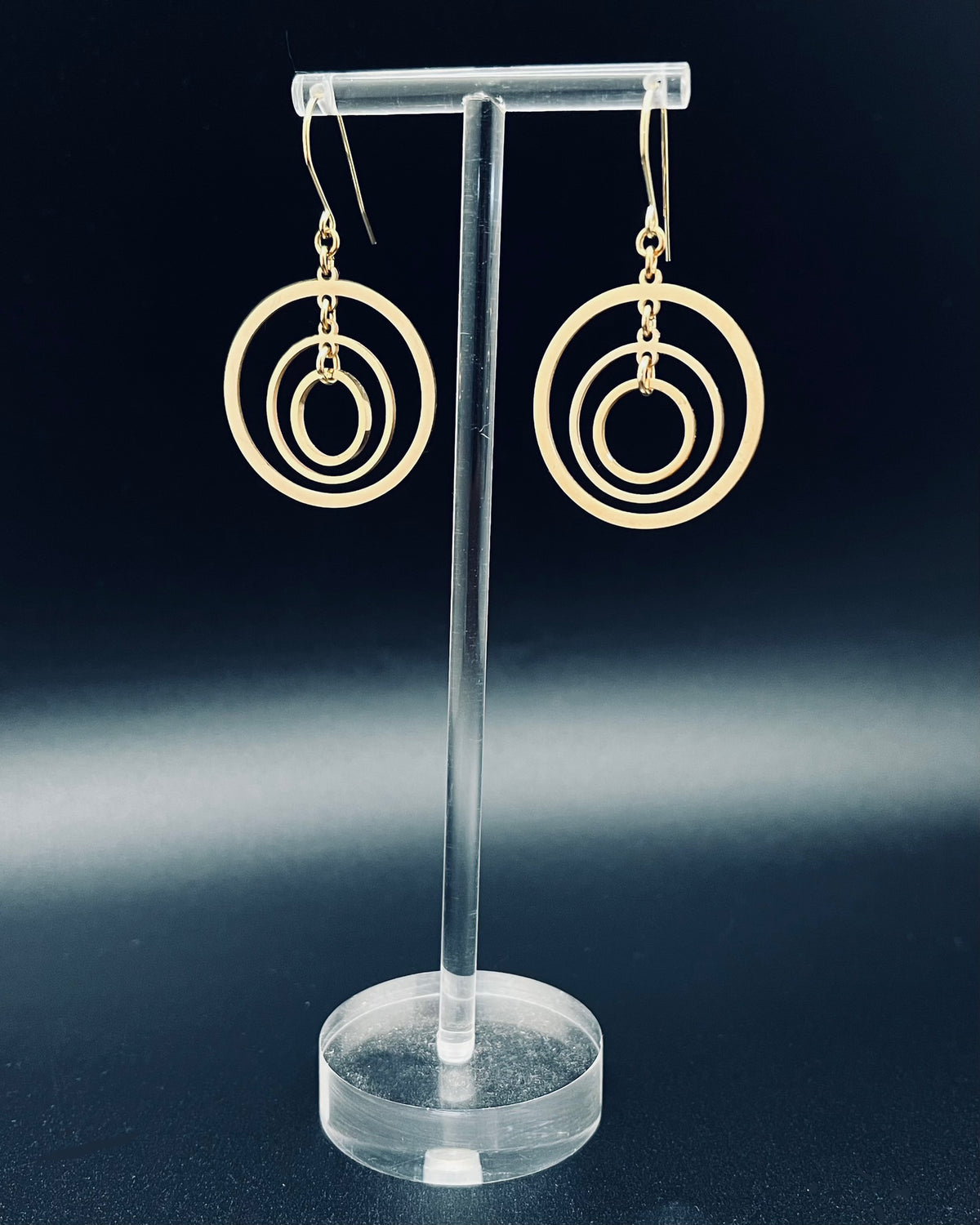Gold triple-ring halo earrings with three interlinked high-polish rings and gold-plated stainless steel ear hooks, 5 cm length — Lawless Jewellery.