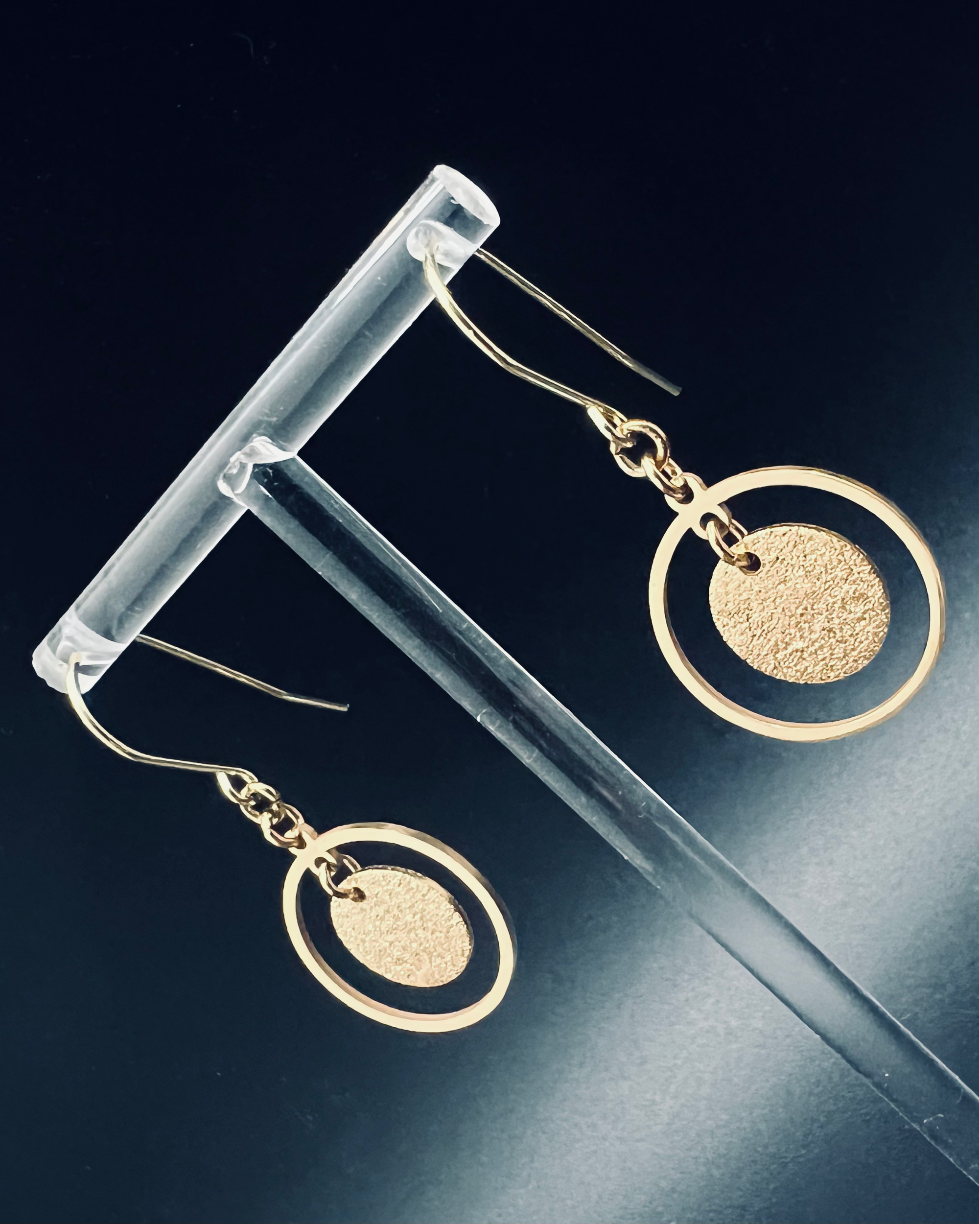 Gold stainless steel halo earrings featuring a circular frame with a textured gold disc suspended inside, lightweight 4 cm design — Lawless Jewellery.