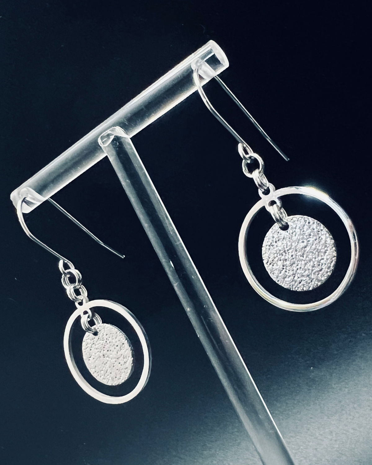 Silver stainless steel halo earrings with a circular frame and suspended textured disc, minimalist 4 cm design — Lawless Jewellery.