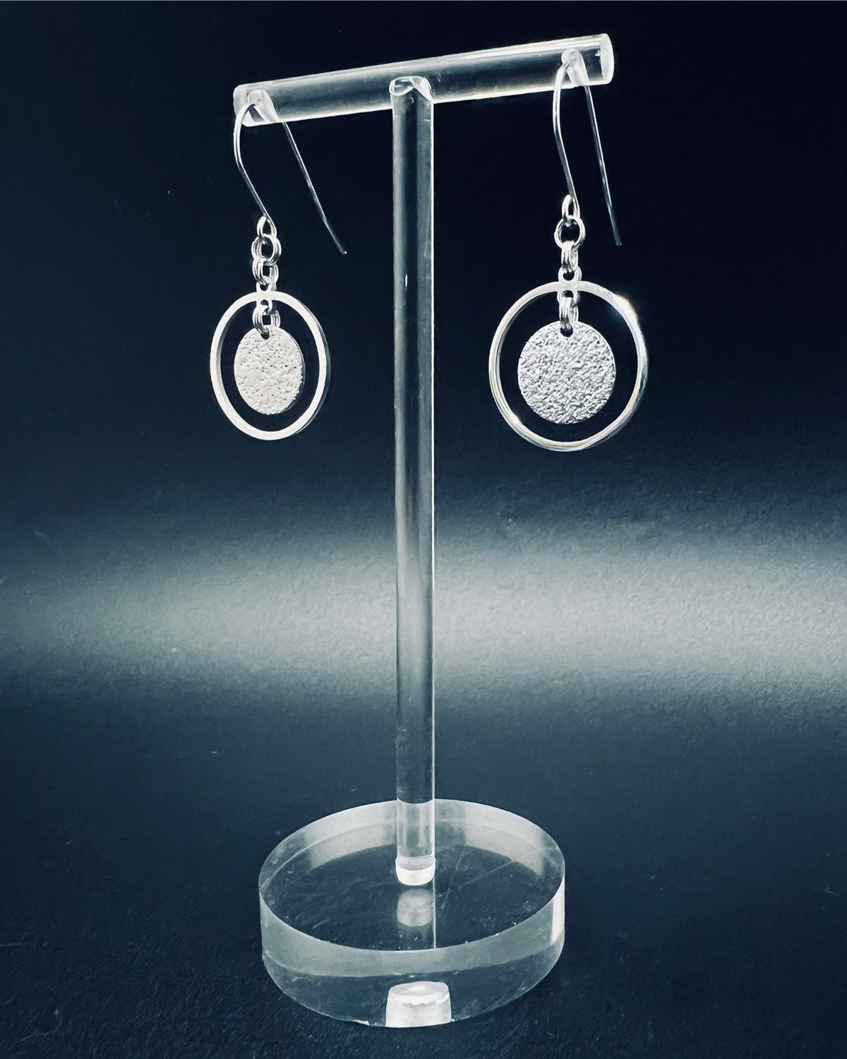 Silver stainless steel halo earrings with a circular frame and suspended textured disc, minimalist 4 cm design — Lawless Jewellery.