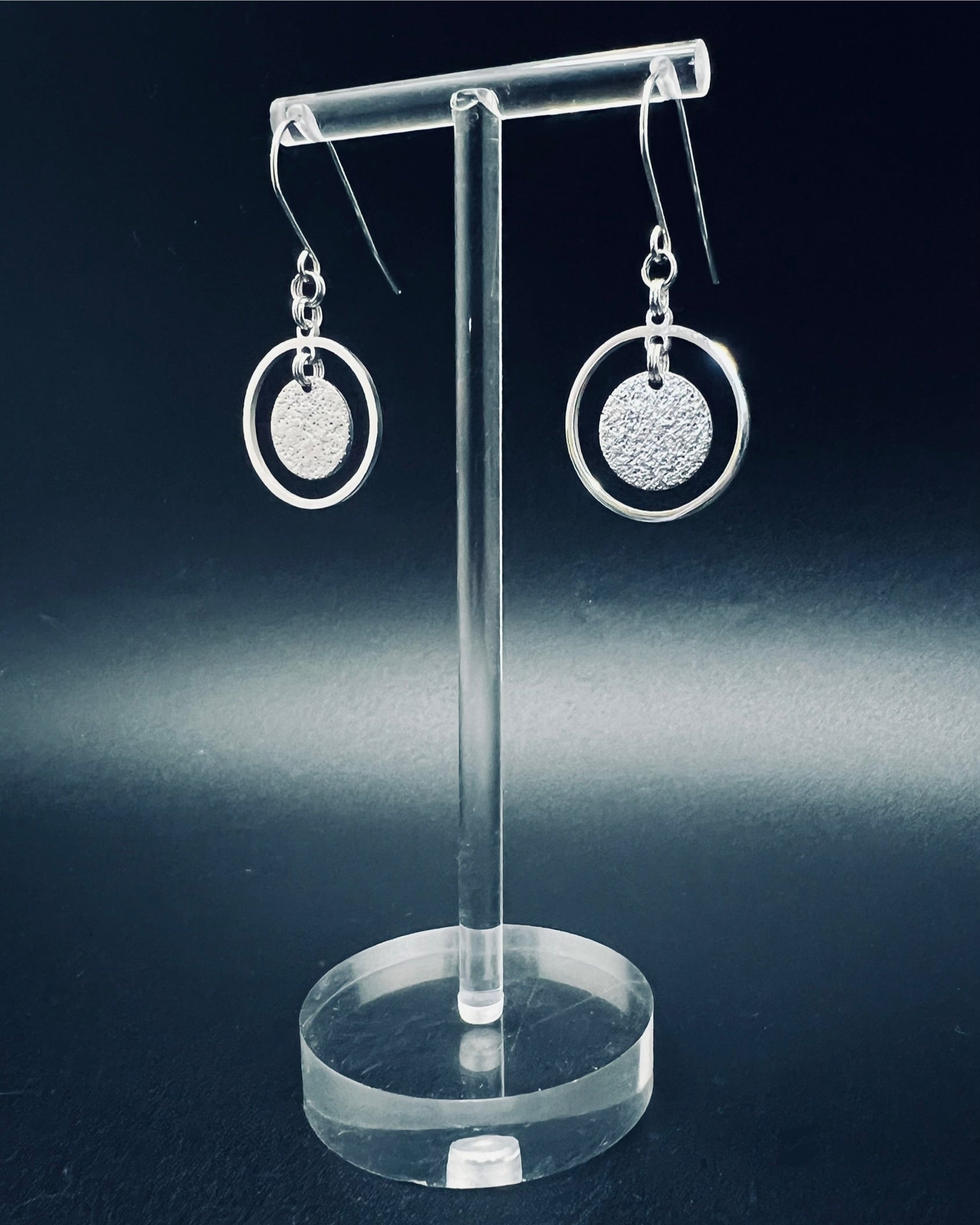 Silver stainless steel halo earrings with a circular frame and suspended textured disc, minimalist 4 cm design — Lawless Jewellery.