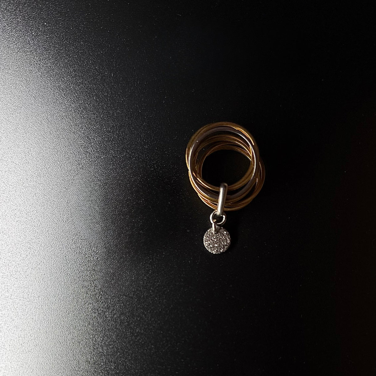 Gold stainless steel fidget ring featuring seven silver bands, one rotating silver band, and a suspended textured gold disc — Lawless Jewellery.