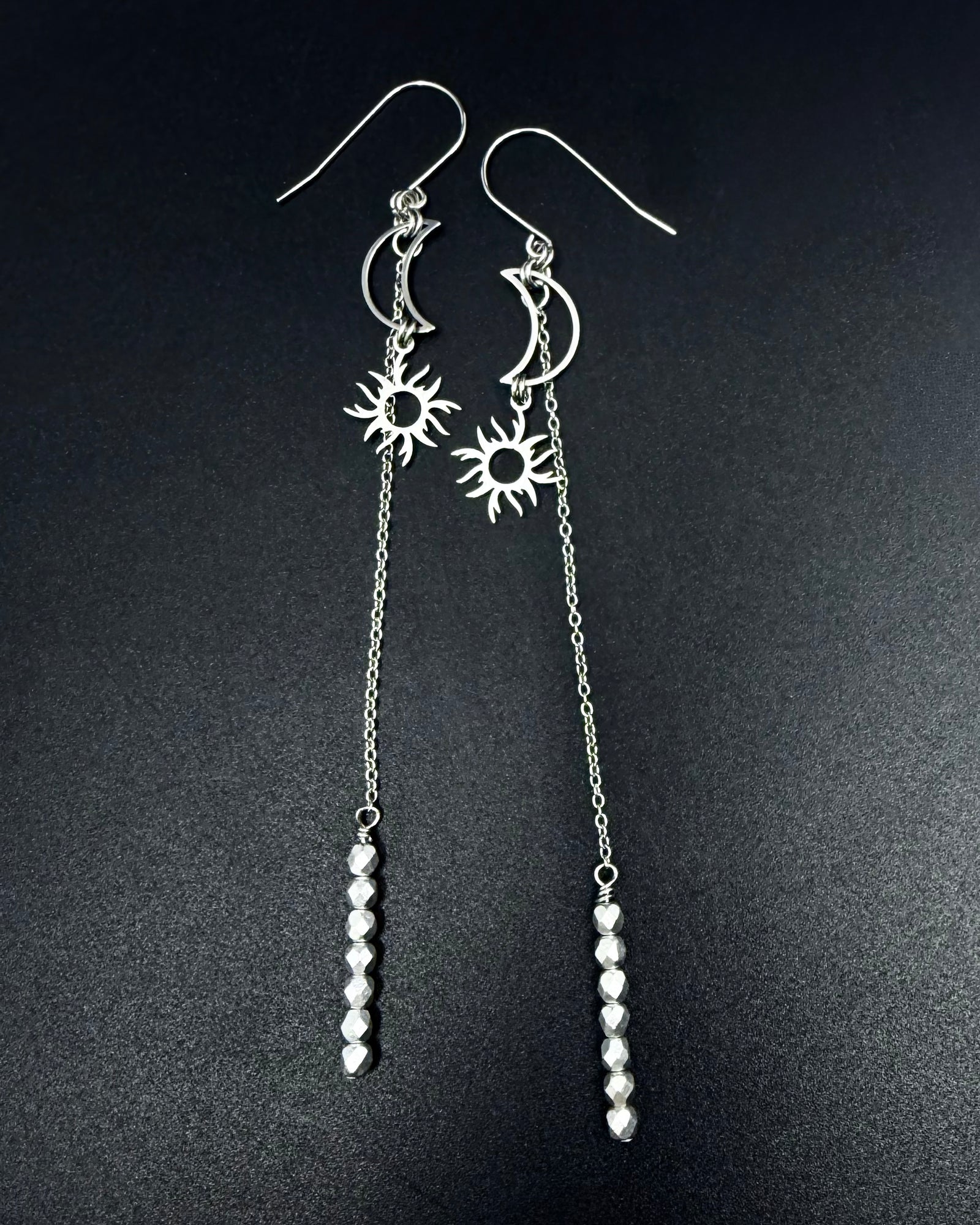 Long silver celestial earrings with crescent moon and sun charms, extended chain and fire-polished crystal, Eos Threshold Earrings by Lawless Jewellery.