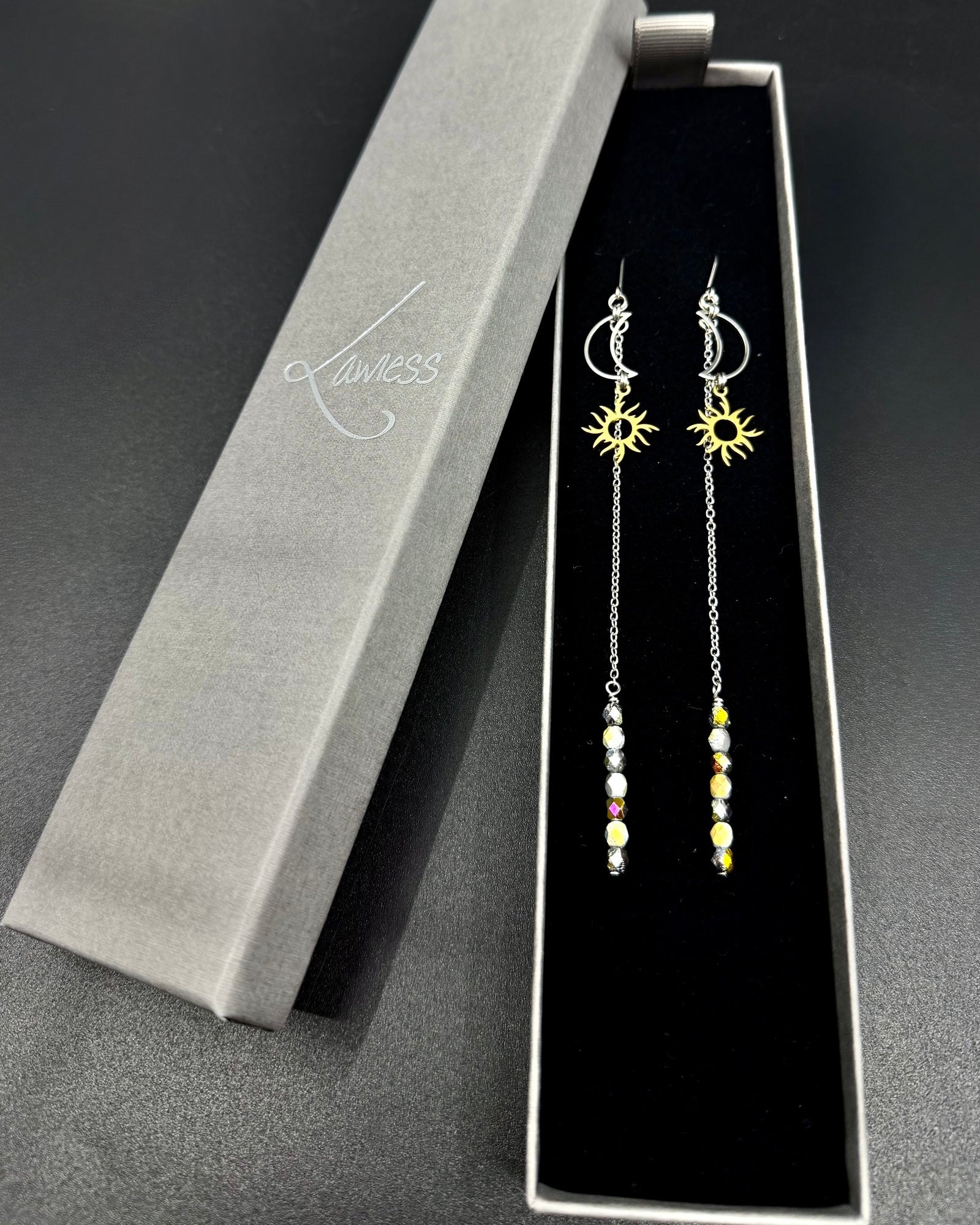 Long mixed-metal celestial earrings with silver crescent moon, gold sun charm, extended chain and fire-polished crystal, Eos Threshold Earrings by Lawless Jewellery.