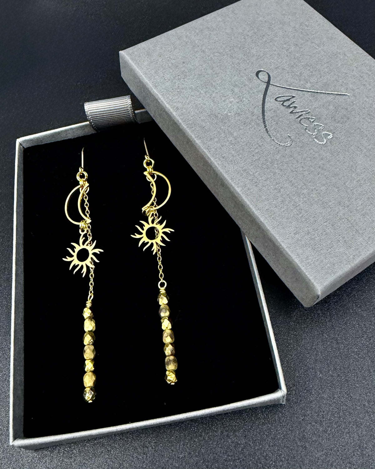 Long gold celestial earrings featuring sun and moon charms with fire-polished crystal drops from the Lawless Eos Threshold collection