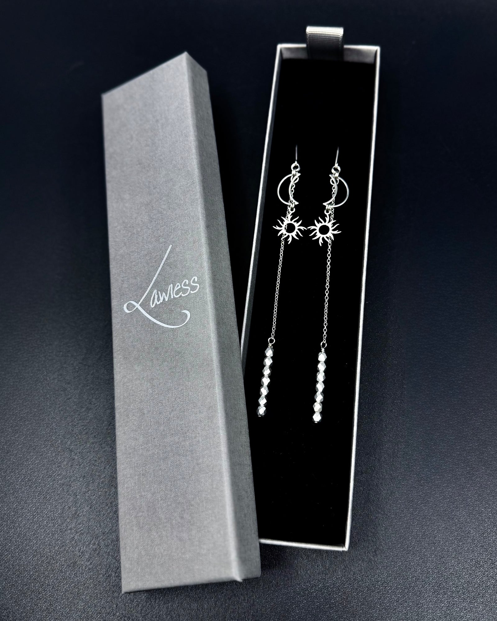 Long silver celestial earrings with crescent moon and sun charms, extended chain and fire-polished crystal, Eos Threshold Earrings by Lawless Jewellery.