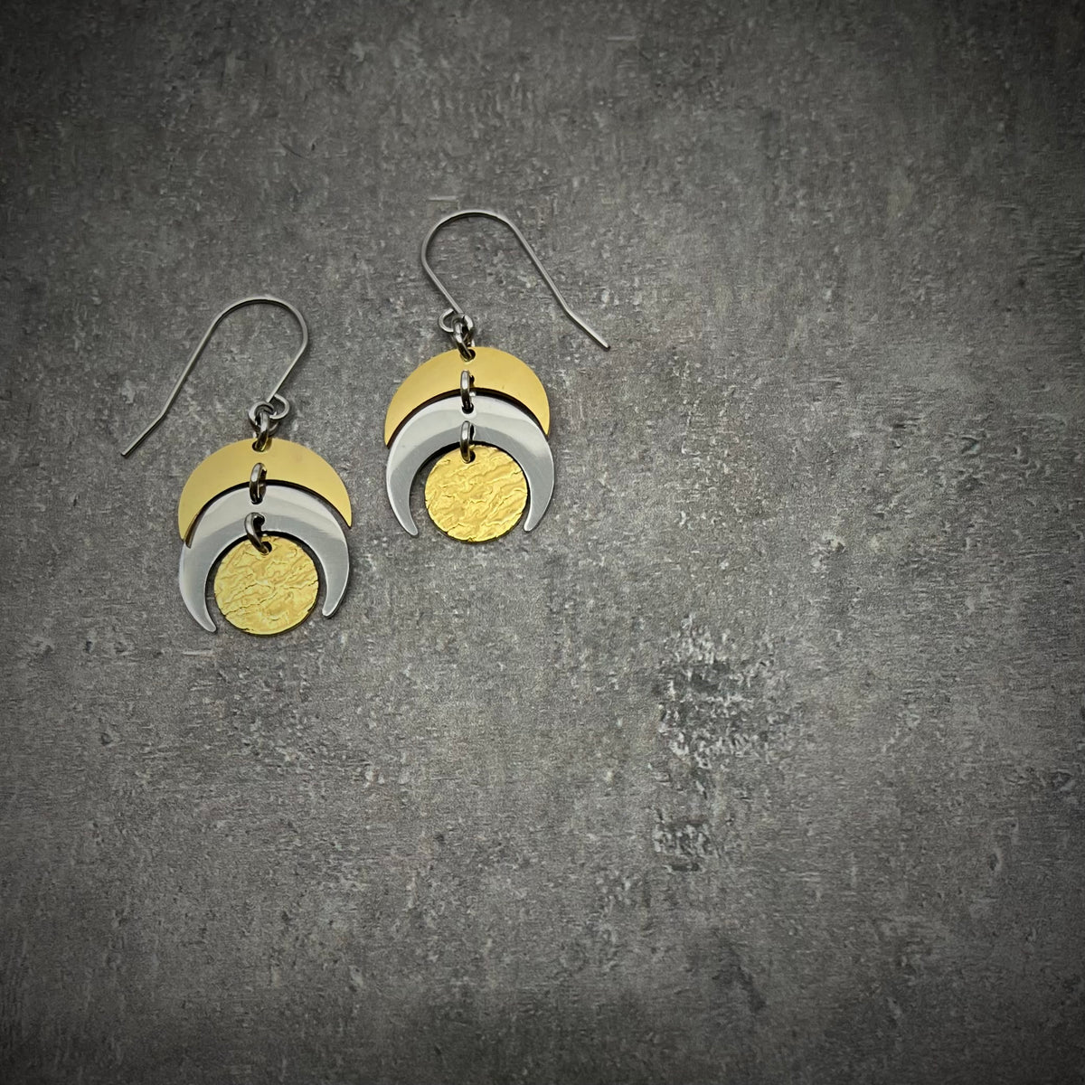 Mixed-metal lunar earrings featuring silver and gold crescents with a textured gold disc, 20 mm wide with a 4 cm drop — Lawless Jewellery.