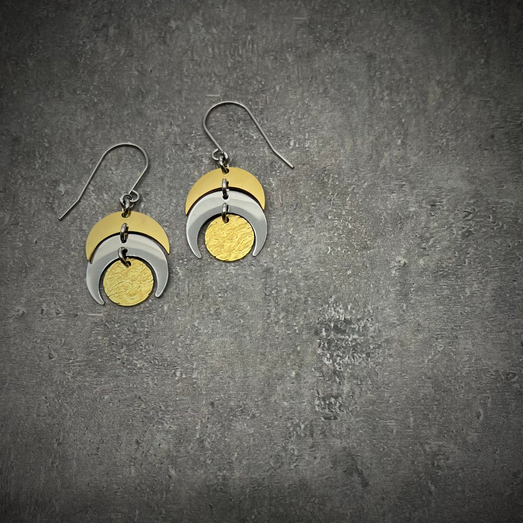 Mixed-metal lunar earrings featuring silver and gold crescents with a textured gold disc, 20 mm wide with a 4 cm drop — Lawless Jewellery.