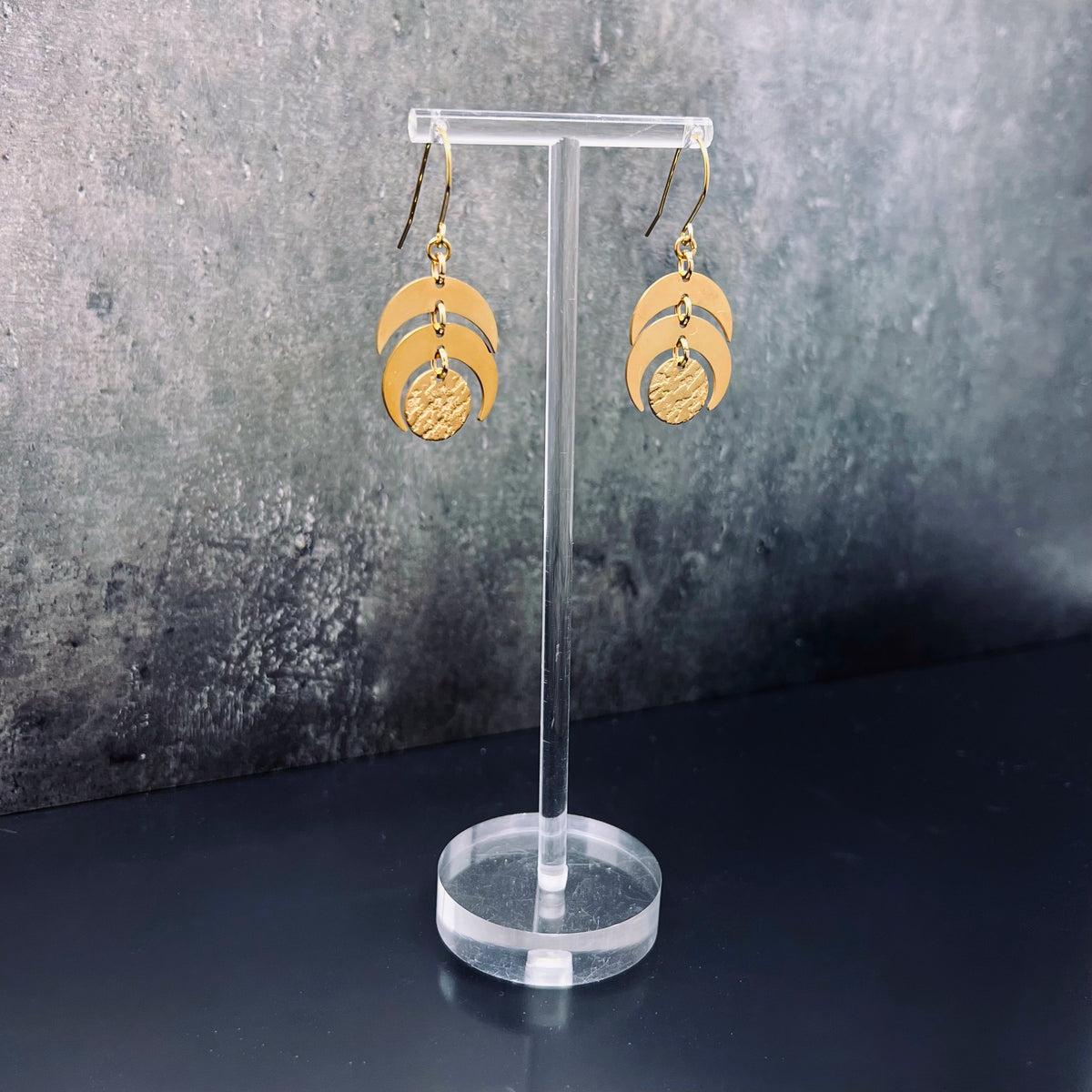 Gold stainless steel lunar-inspired earrings featuring layered crescents and a textured gold disc, 20 mm wide with a 4 cm drop — Lawless Jewellery.