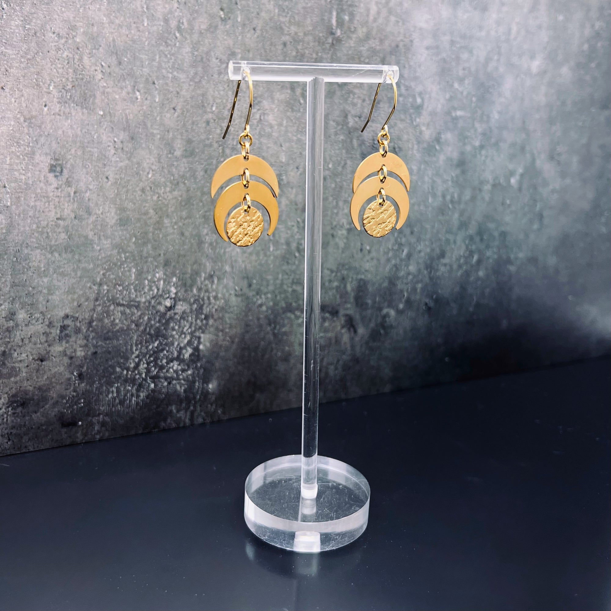 Gold stainless steel lunar-inspired earrings featuring layered crescents and a textured gold disc, 20 mm wide with a 4 cm drop — Lawless Jewellery.