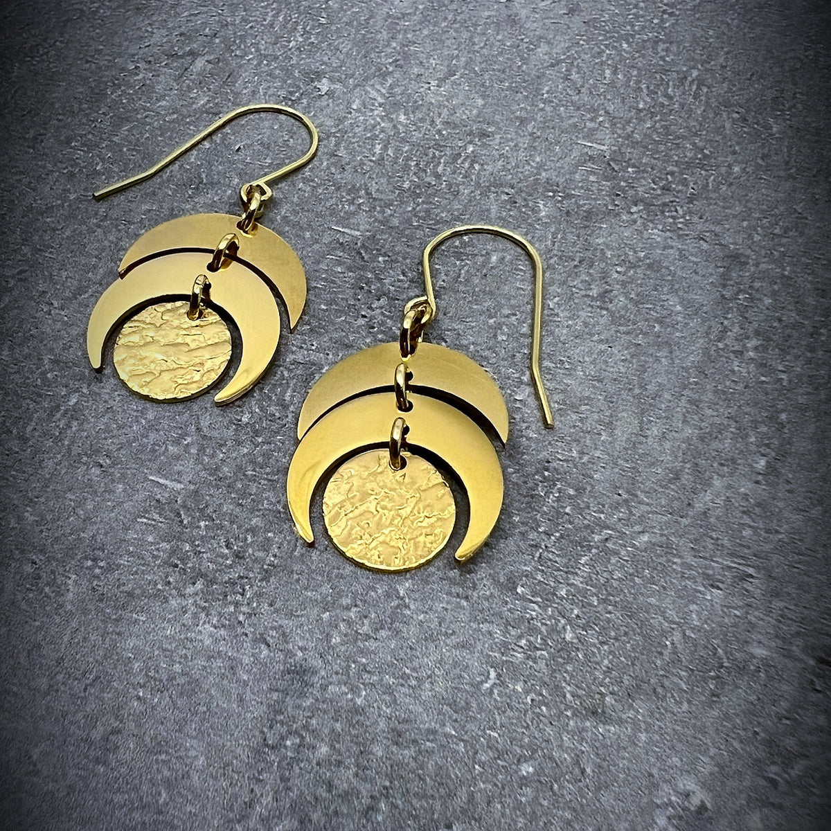 Gold stainless steel lunar-inspired earrings featuring layered crescents and a textured gold disc, 20 mm wide with a 4 cm drop — Lawless Jewellery.