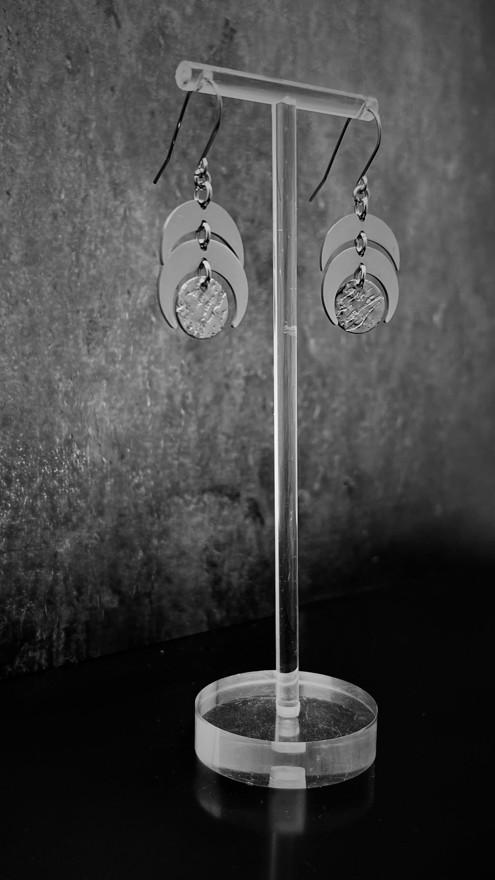 All-silver stainless steel lunar earrings featuring layered crescent shapes with a textured disc, 20 mm wide with a 4 cm drop — Lawless Jewellery.