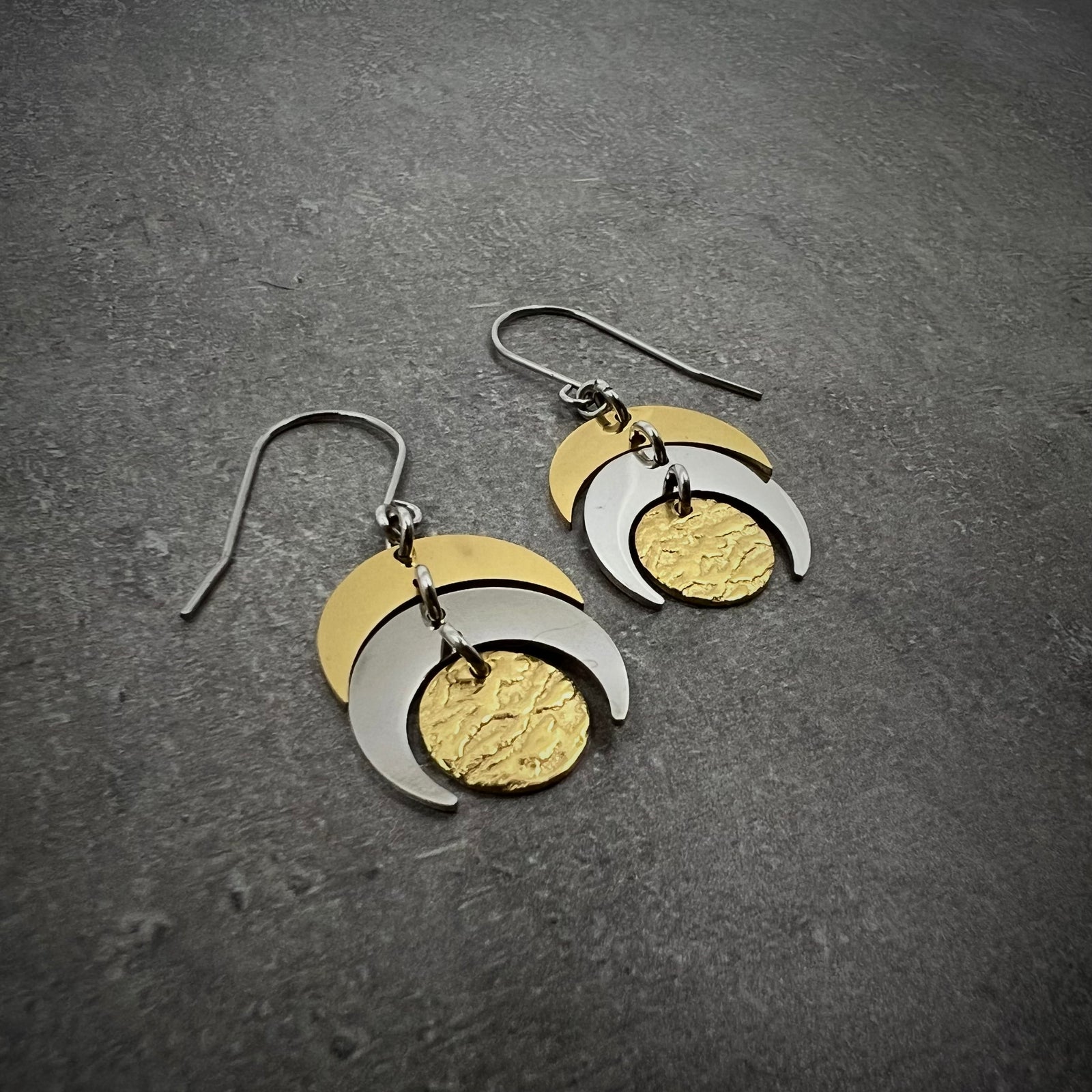 Mixed-metal lunar earrings featuring silver and gold crescents with a textured gold disc, 20 mm wide with a 4 cm drop — Lawless Jewellery.