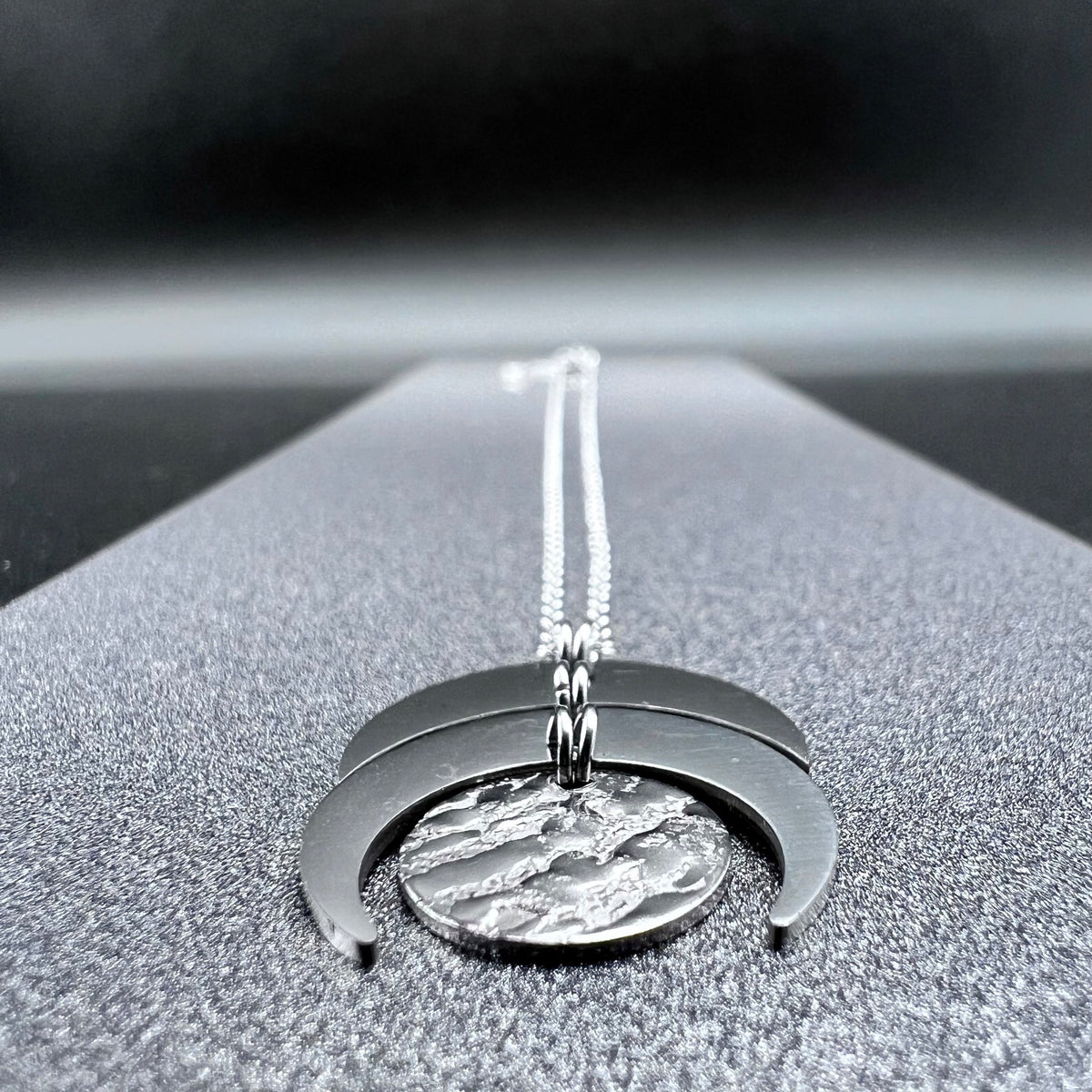 Silver stainless steel Luna Phase necklace with sculptural crescent and disc pendant on an adjustable chain, 20 mm wide — Lawless Jewellery.