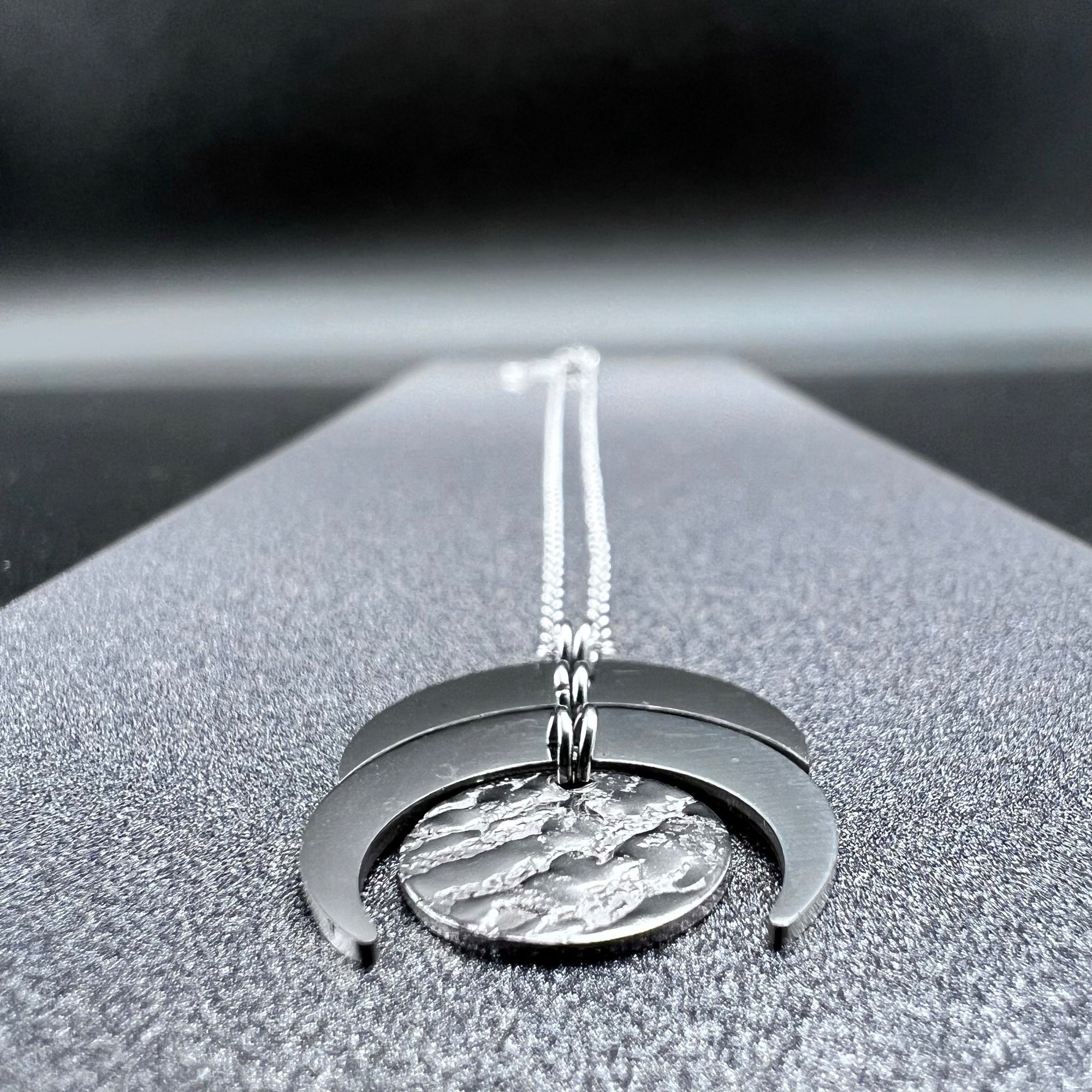 Silver stainless steel Luna Phase necklace with sculptural crescent and disc pendant on an adjustable chain, 20 mm wide — Lawless Jewellery.