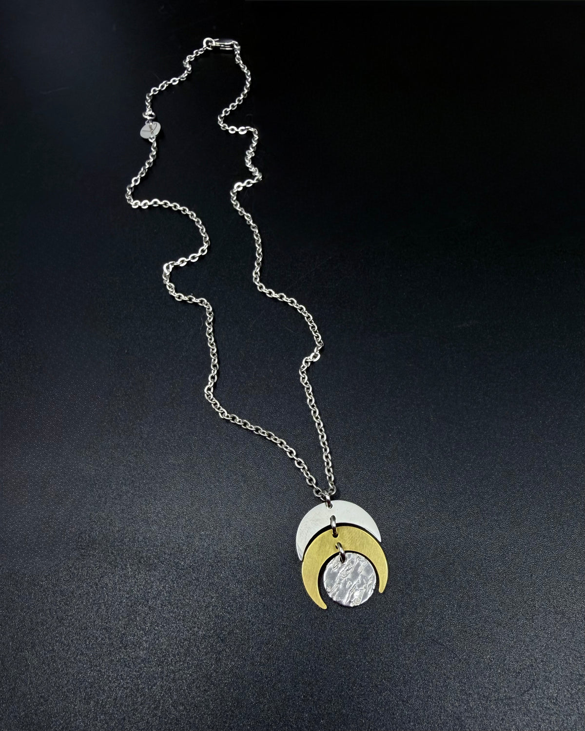 Mixed metal Luna Phase Necklace with silver and gold crescent moon design and textured gold disc on adjustable gold-tone chain