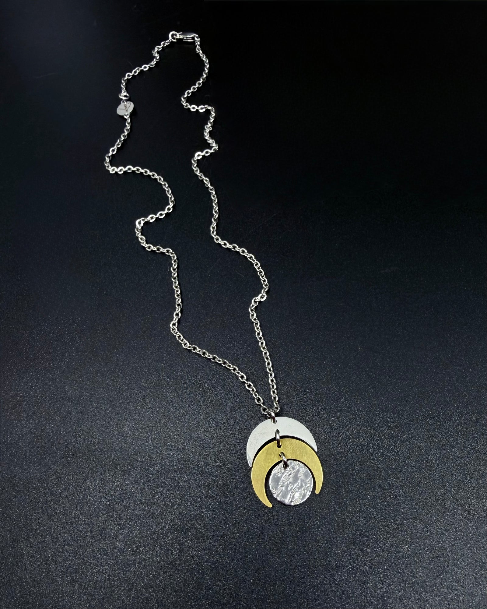 Mixed metal Luna Phase Necklace with silver and gold crescent moon design and textured gold disc on adjustable gold-tone chain