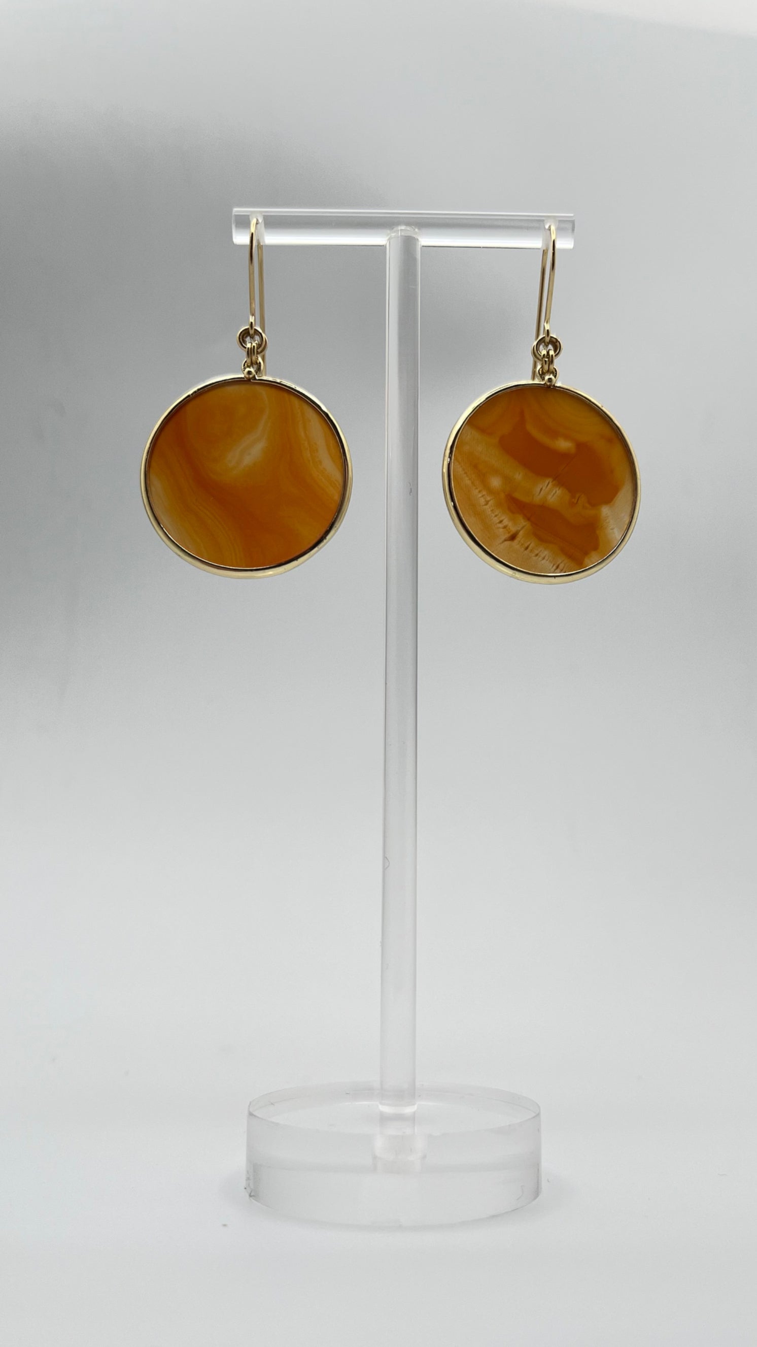 Gold-plated stainless steel earrings with 30 mm polished carnelian gemstone discs showing natural volcanic banding, 5 cm drop — Lawless Jewellery.