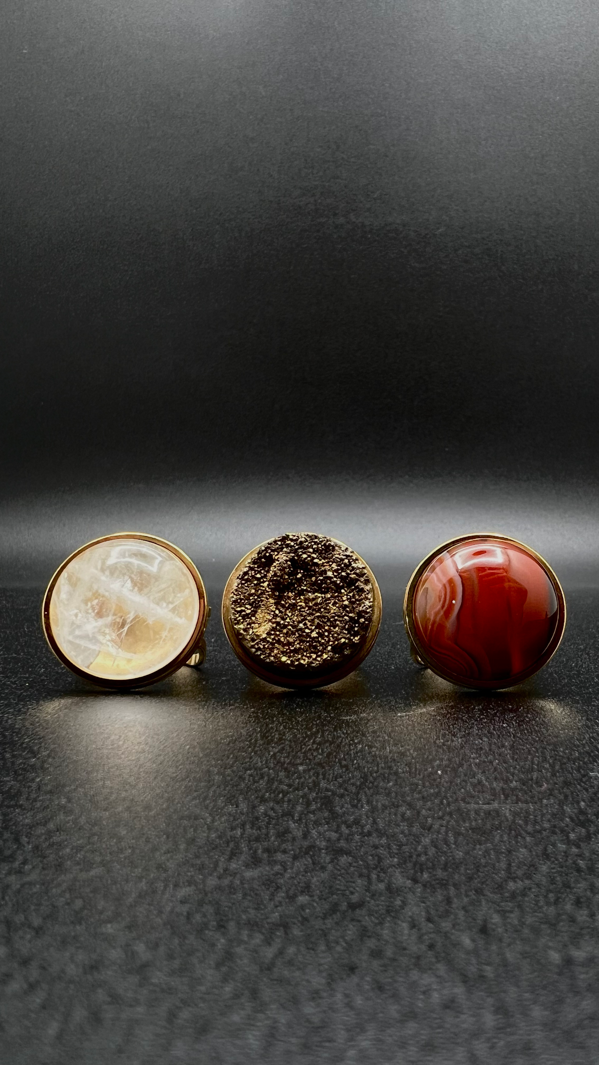 Set of three gold-plated stainless steel rings featuring 20 mm cabochons in Clear Quartz, Gold Druzy, and Carnelian on adjustable double-shank bands — Lawless Jewellery.