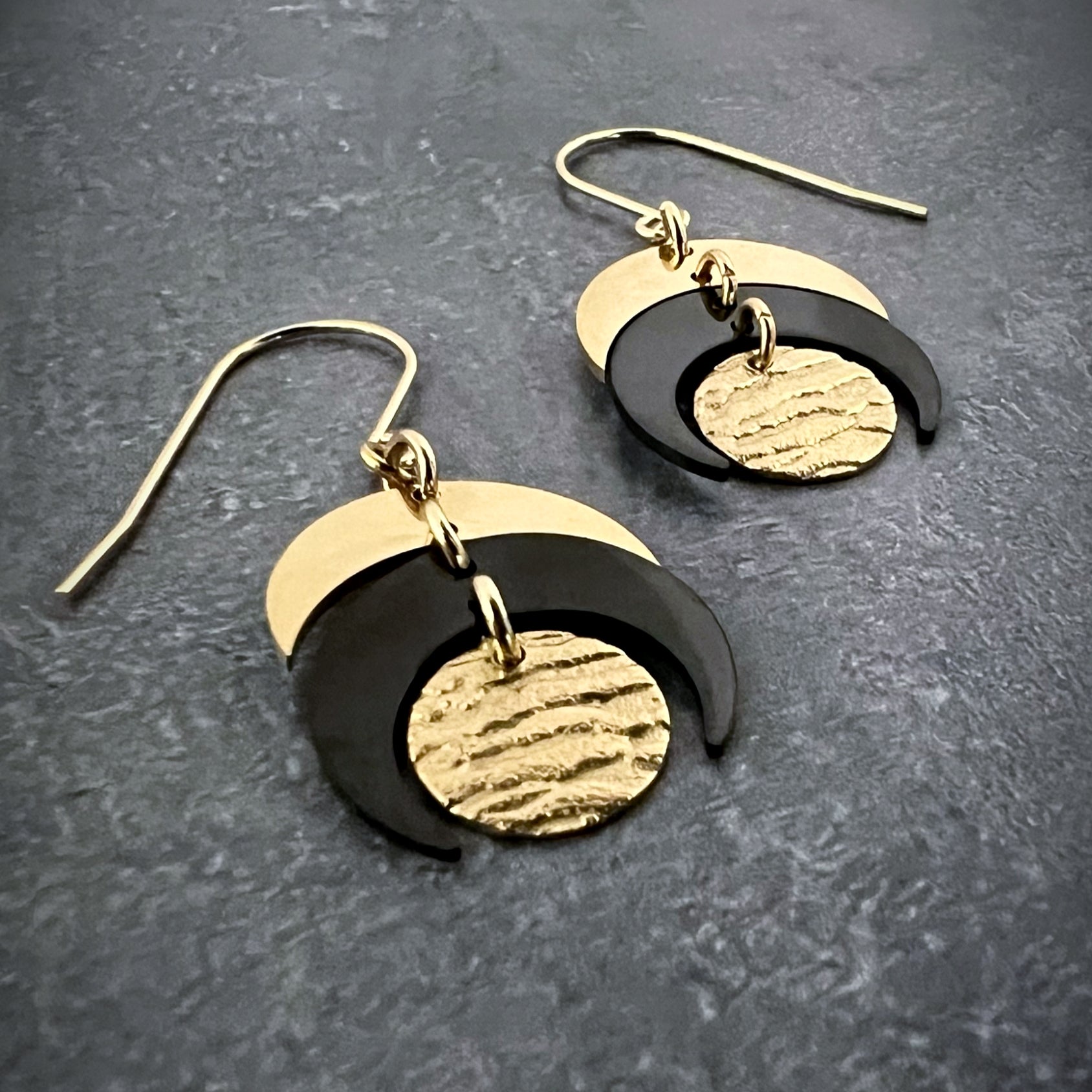 Gold and black stainless steel earrings with crescent and textured disc design inspired by lunar phases, lightweight and hypoallergenic — Lawless Jewellery.