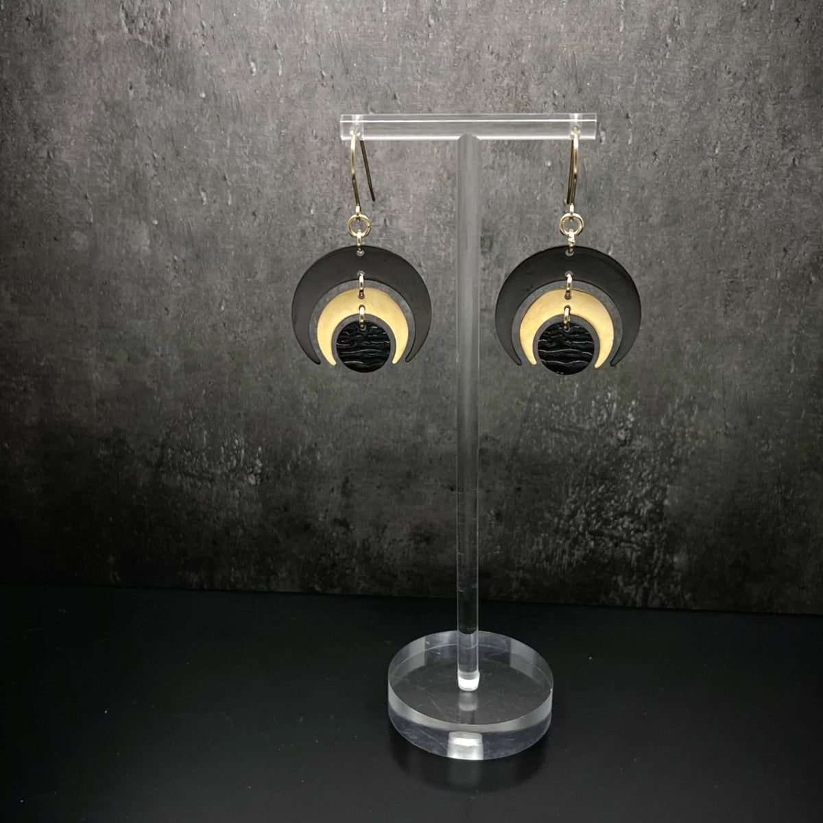 Gold and black stainless steel statement earrings featuring crescent moon and dark disc design, bold and lightweight — Lawless Jewellery.
