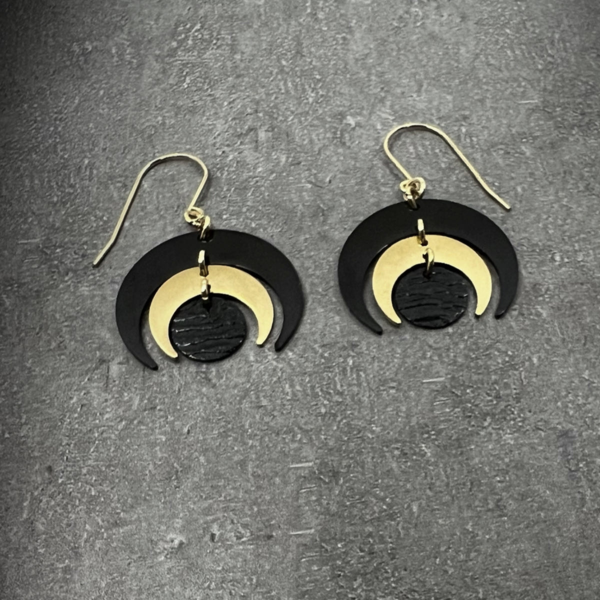 Gold and black stainless steel statement earrings featuring crescent moon and dark disc design, bold and lightweight — Lawless Jewellery.