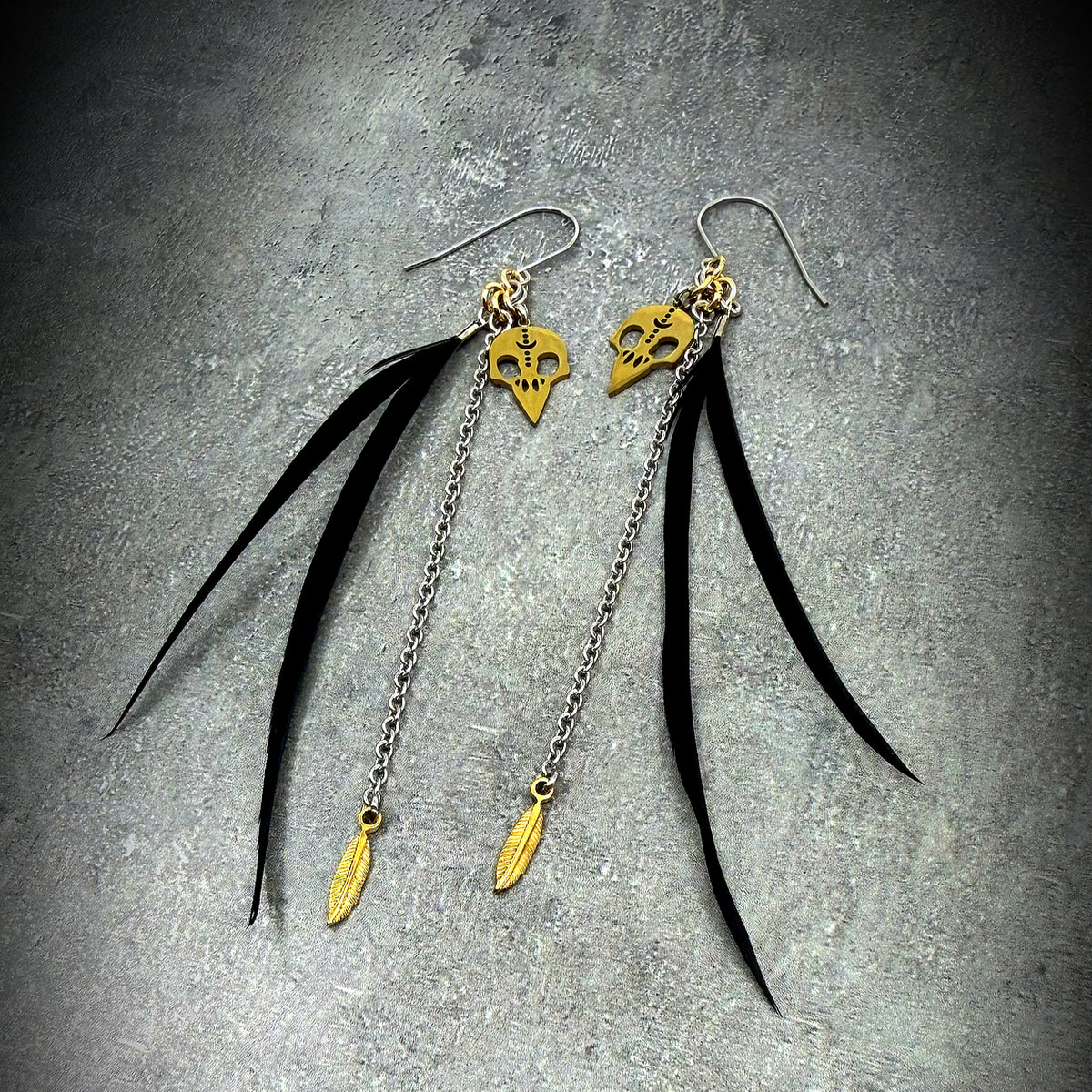 Black, silver, and gold stainless steel earrings with real feather detailing and chain accents — lightweight statement design — Lawless Jewellery.