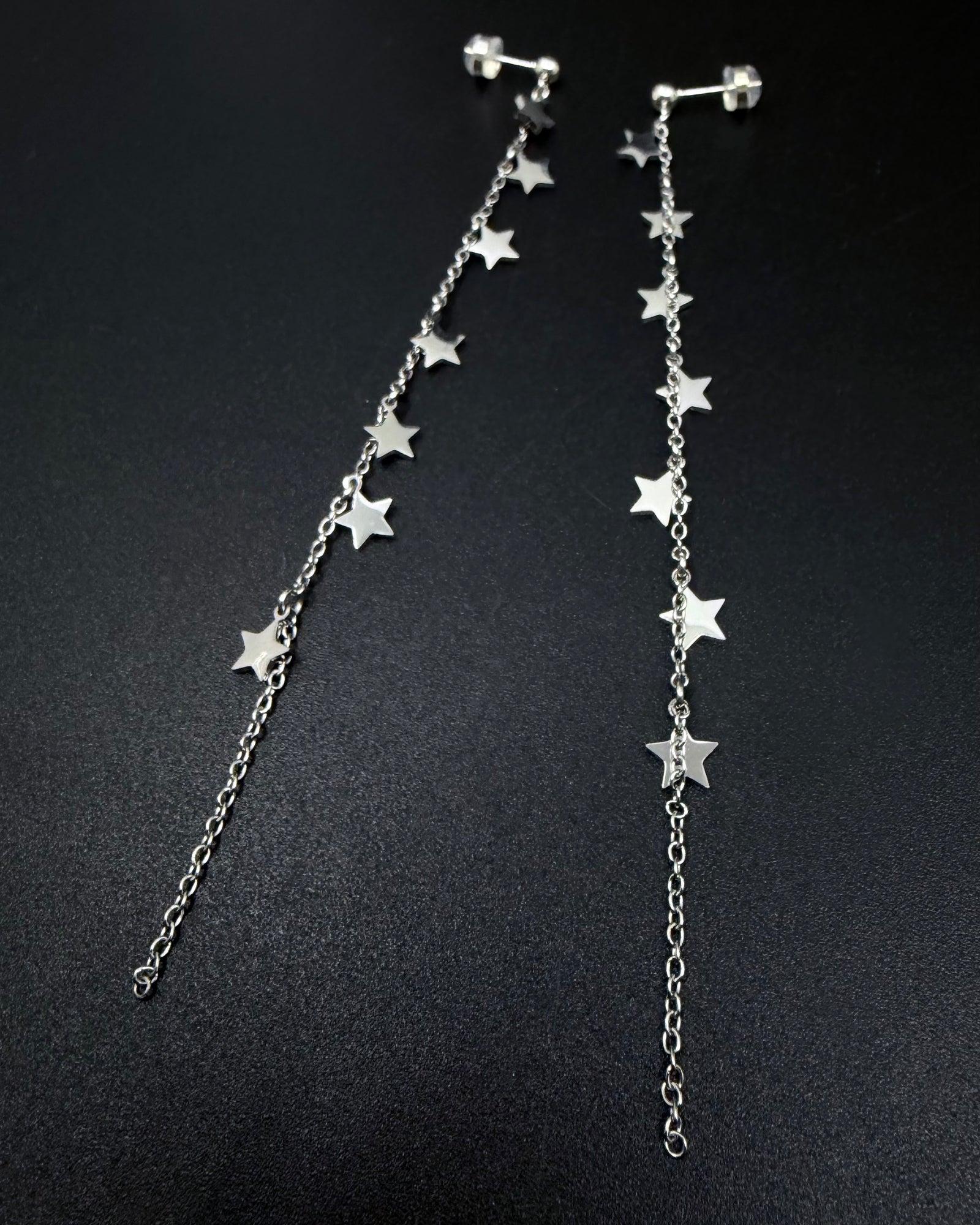 Long silver celestial drop earrings with multiple star charms on fine stainless steel chains, Urania Meridian Earrings by Lawless Jewellery