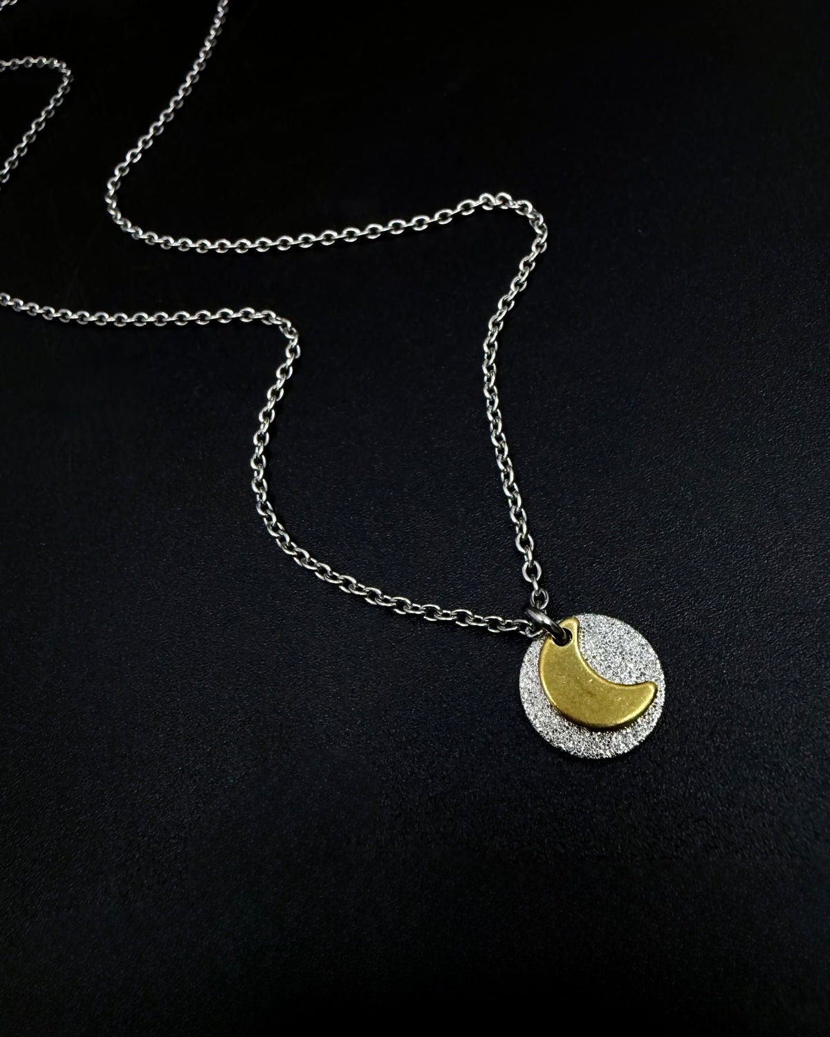 Mixed metal Urania Signal necklace with silver textured disc and gold crescent moon pendant on adjustable stainless steel chain.