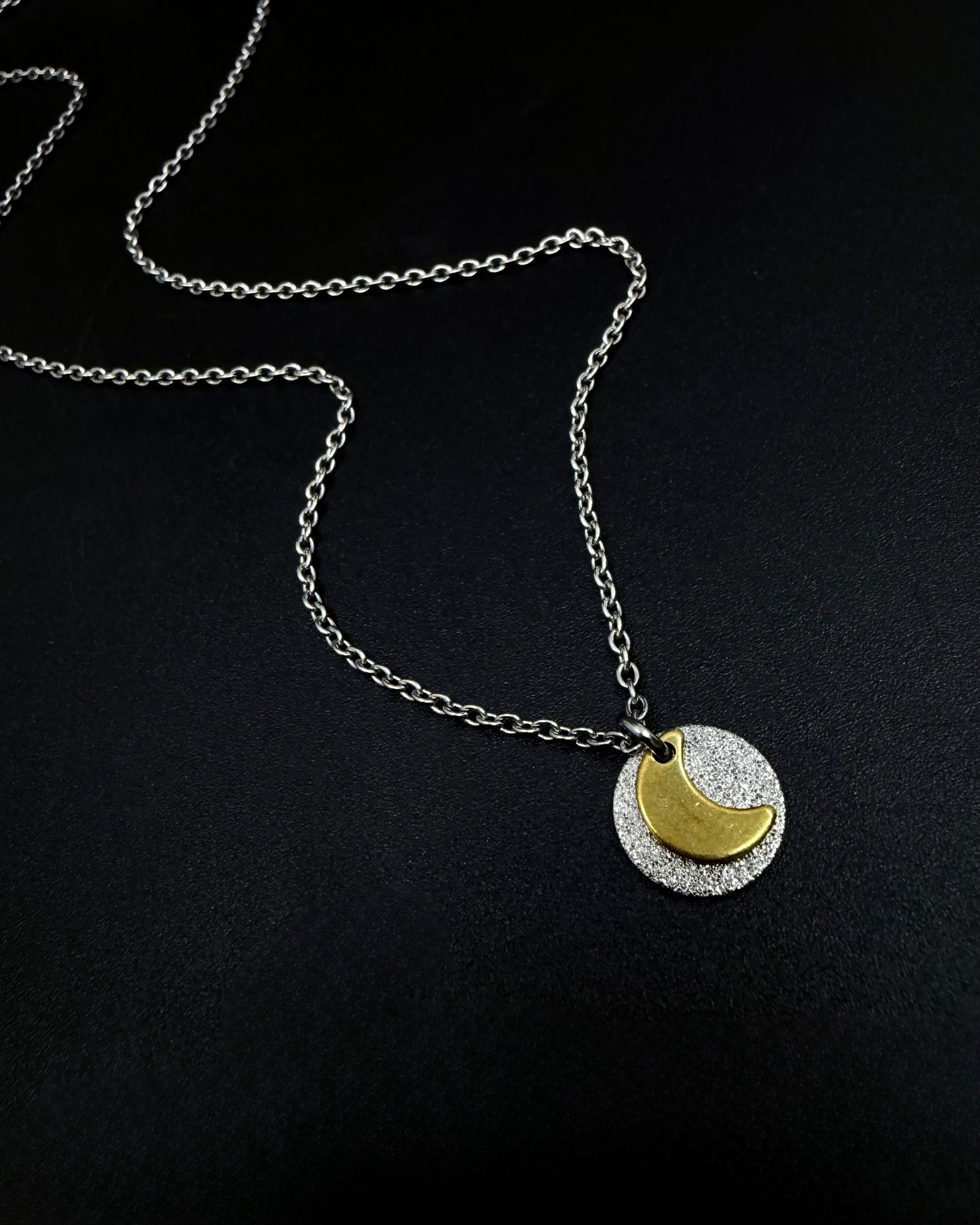 Mixed metal Urania Signal necklace with silver textured disc and gold crescent moon pendant on adjustable stainless steel chain.