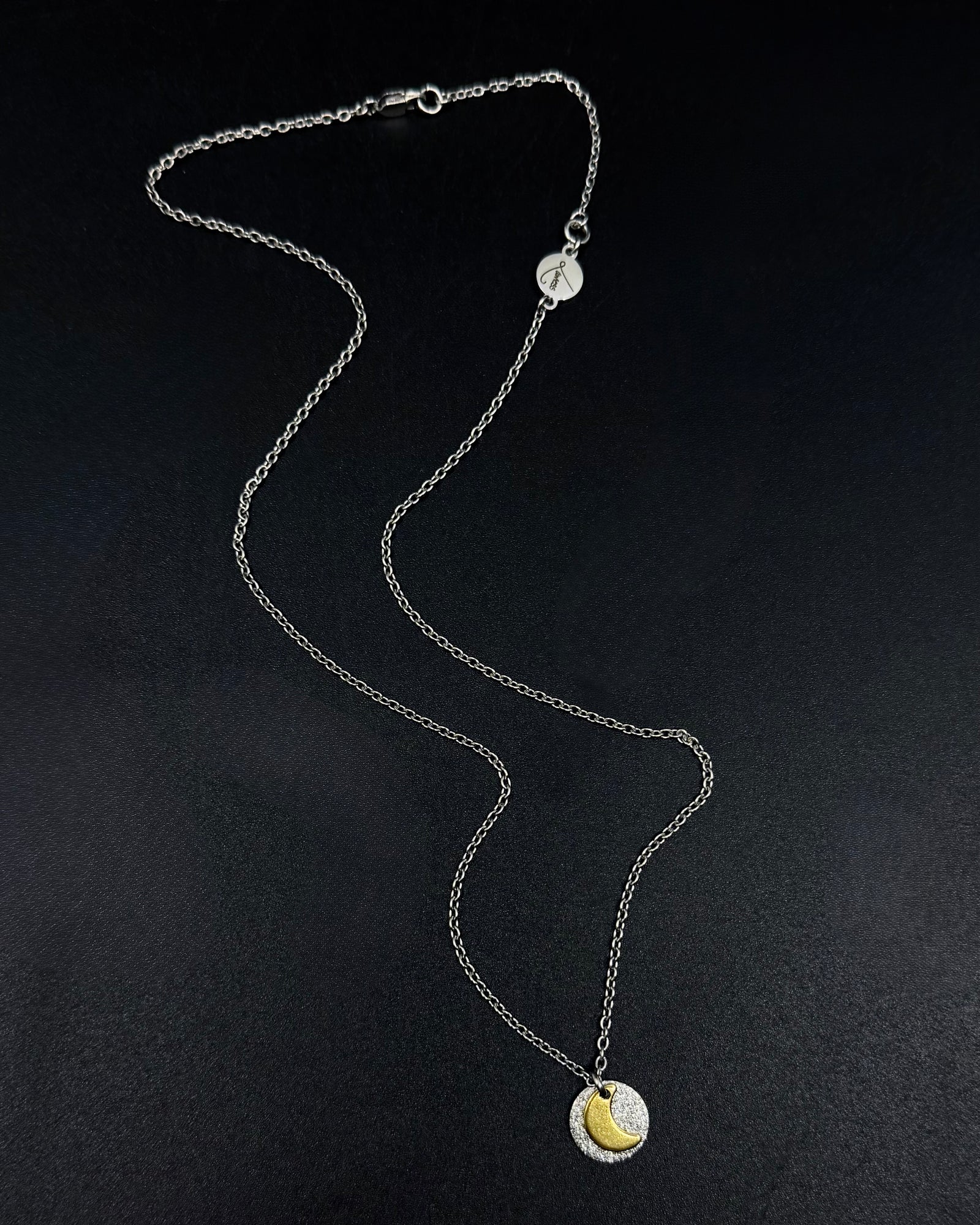 Mixed metal Urania Signal necklace with silver textured disc and gold crescent moon pendant on adjustable stainless steel chain.