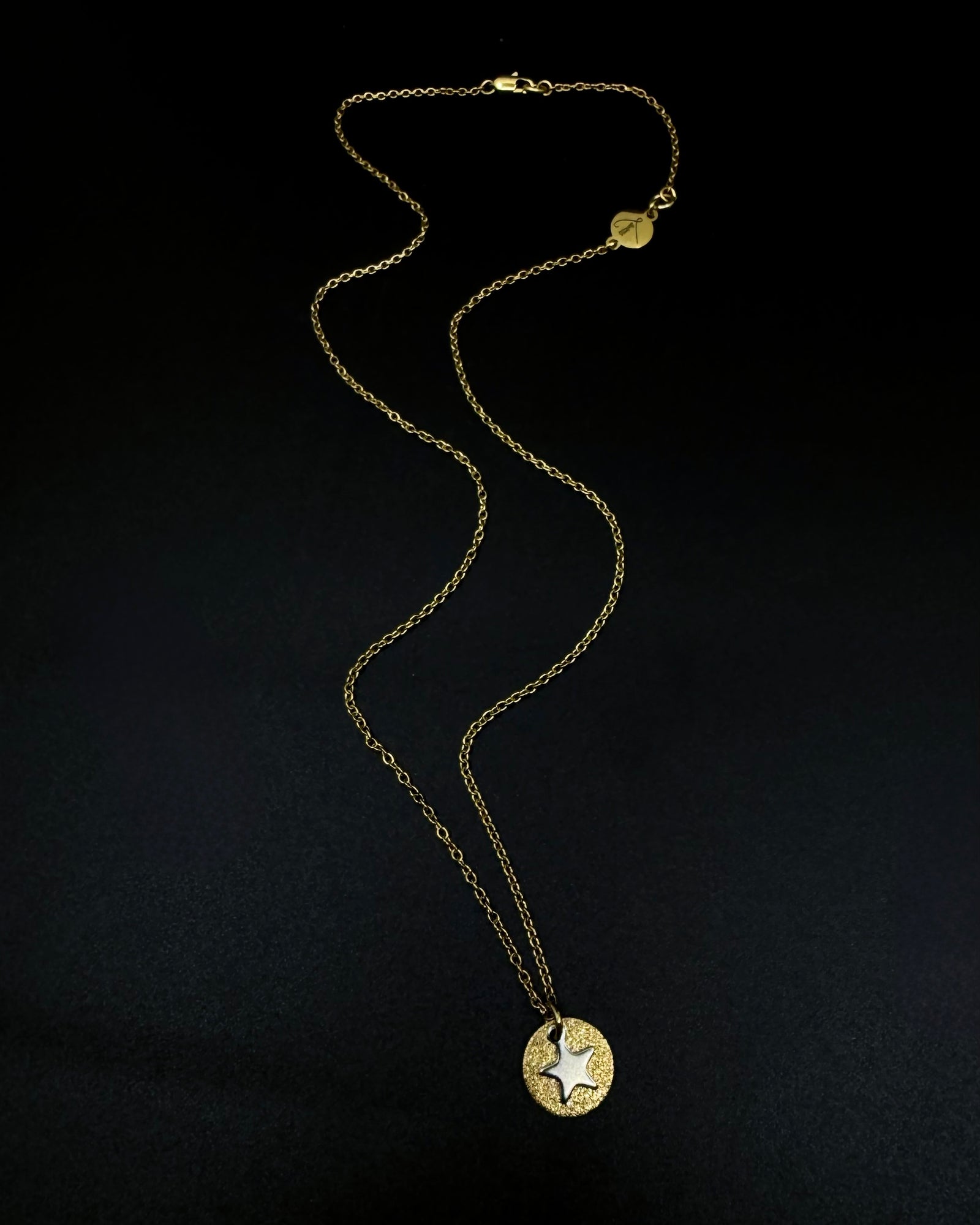 Gold and silver Urania Signal Star Necklace with textured gold disc and polished silver star charm on an adjustable stainless steel chain.
