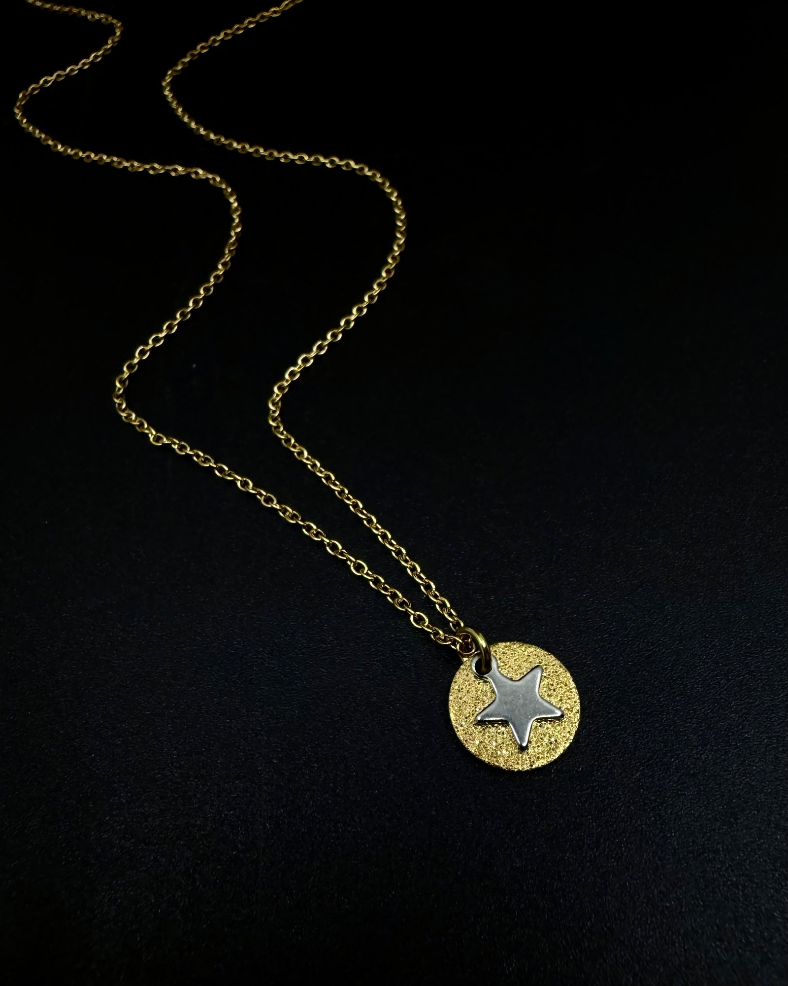 Gold and silver Urania Signal Star Necklace with textured gold disc and polished silver star charm on an adjustable stainless steel chain.