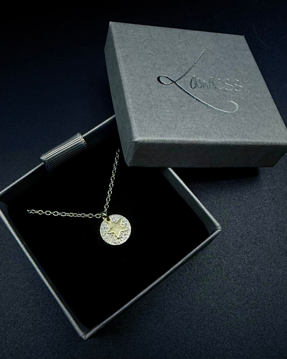 Silver and gold Urania Signal Star Necklace featuring a textured silver disc with a polished gold star charm on an adjustable stainless steel chain