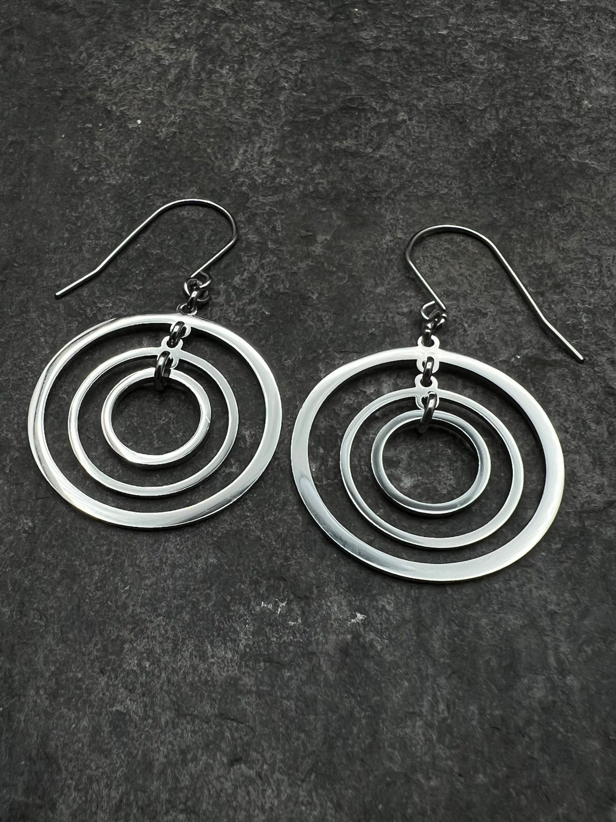 Silver stainless steel triple-ring earrings with three interlinked high-polish rings and stainless steel hooks, 5 cm length — Lawless Jewellery.