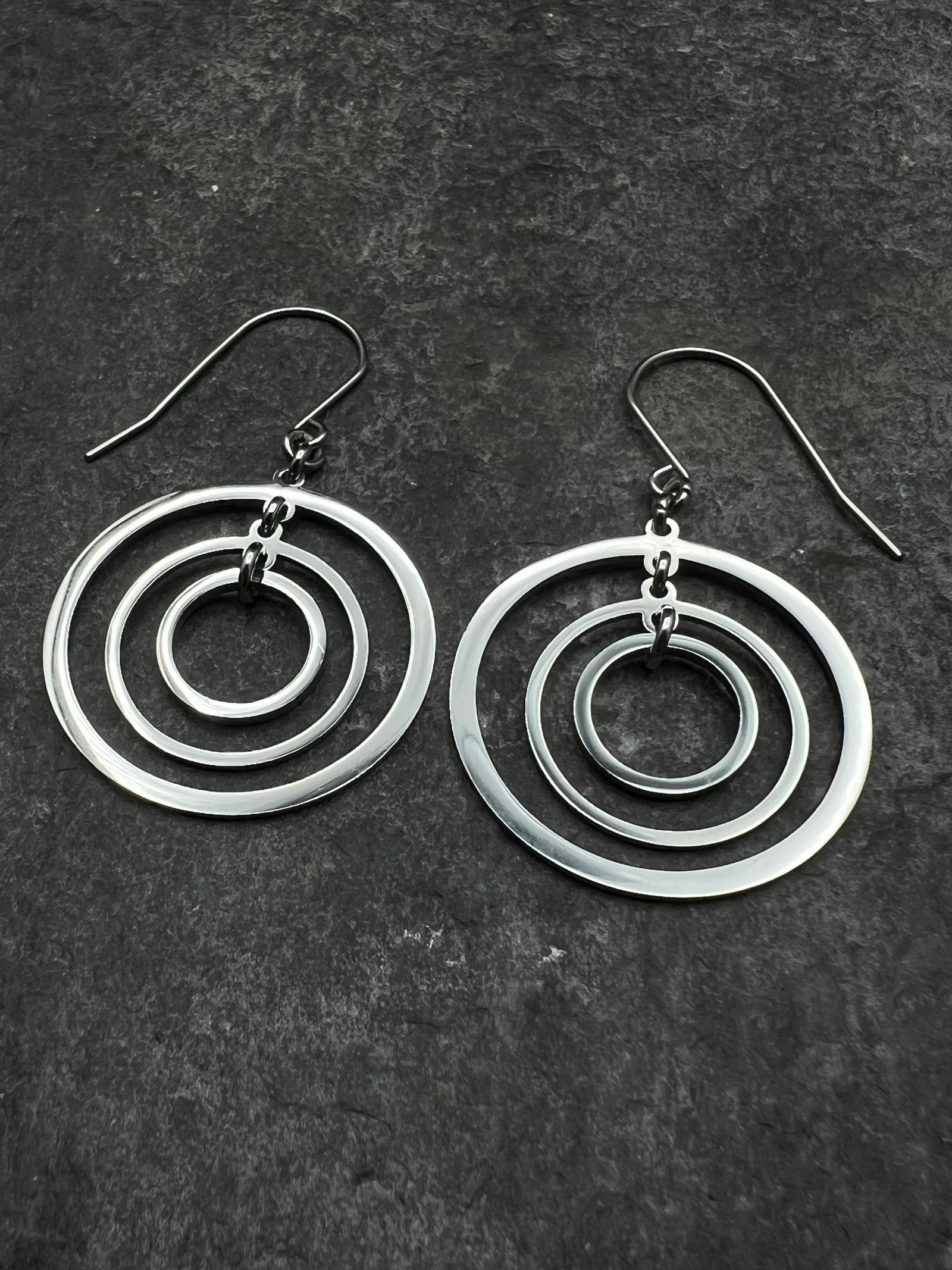 Silver stainless steel triple-ring earrings with three interlinked high-polish rings and stainless steel hooks, 5 cm length — Lawless Jewellery.