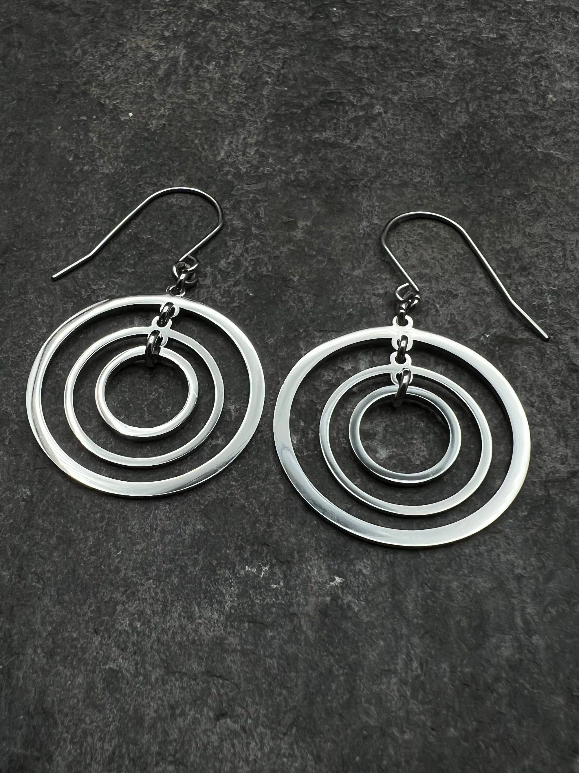 Silver stainless steel triple-ring earrings with three interlinked high-polish rings and stainless steel hooks, 5 cm length — Lawless Jewellery.
