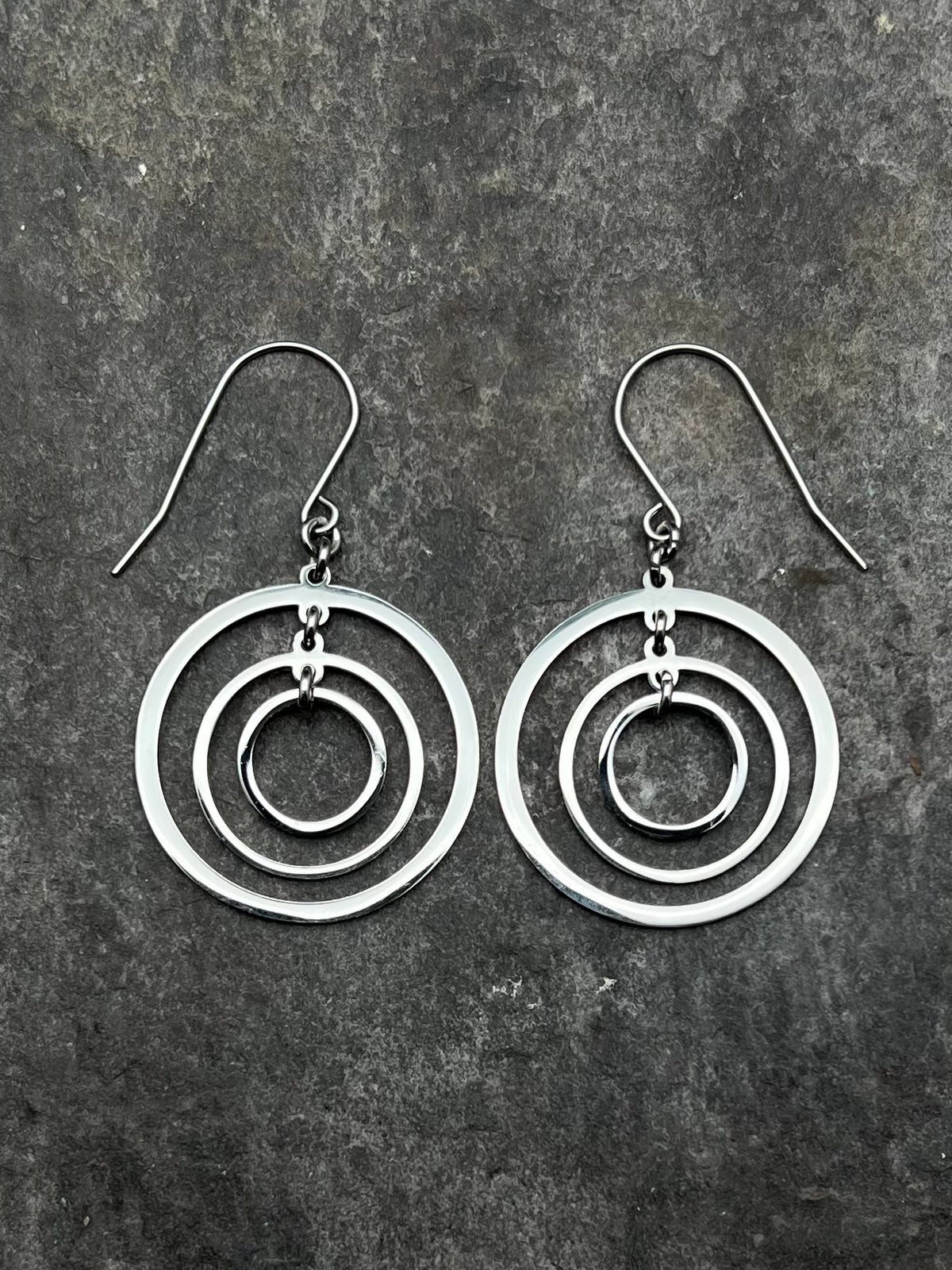 Silver stainless steel triple-ring earrings with three interlinked high-polish rings and stainless steel hooks, 5 cm length — Lawless Jewellery.