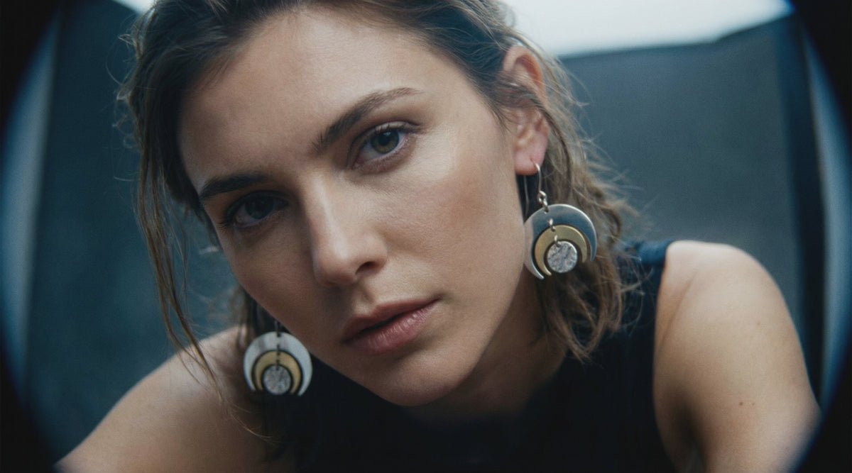 A woman wears the Luna Phase 30mm mixed metal earrings from lawless Jewellery