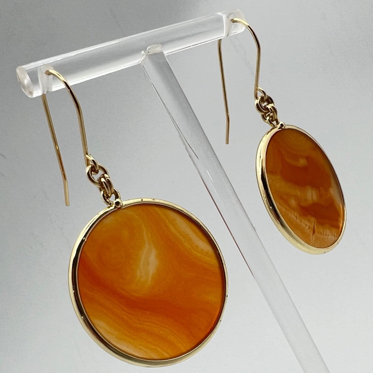 Gold-plated stainless steel earrings with 30 mm polished carnelian gemstone discs showing natural volcanic banding, 5 cm drop — Lawless Jewellery.